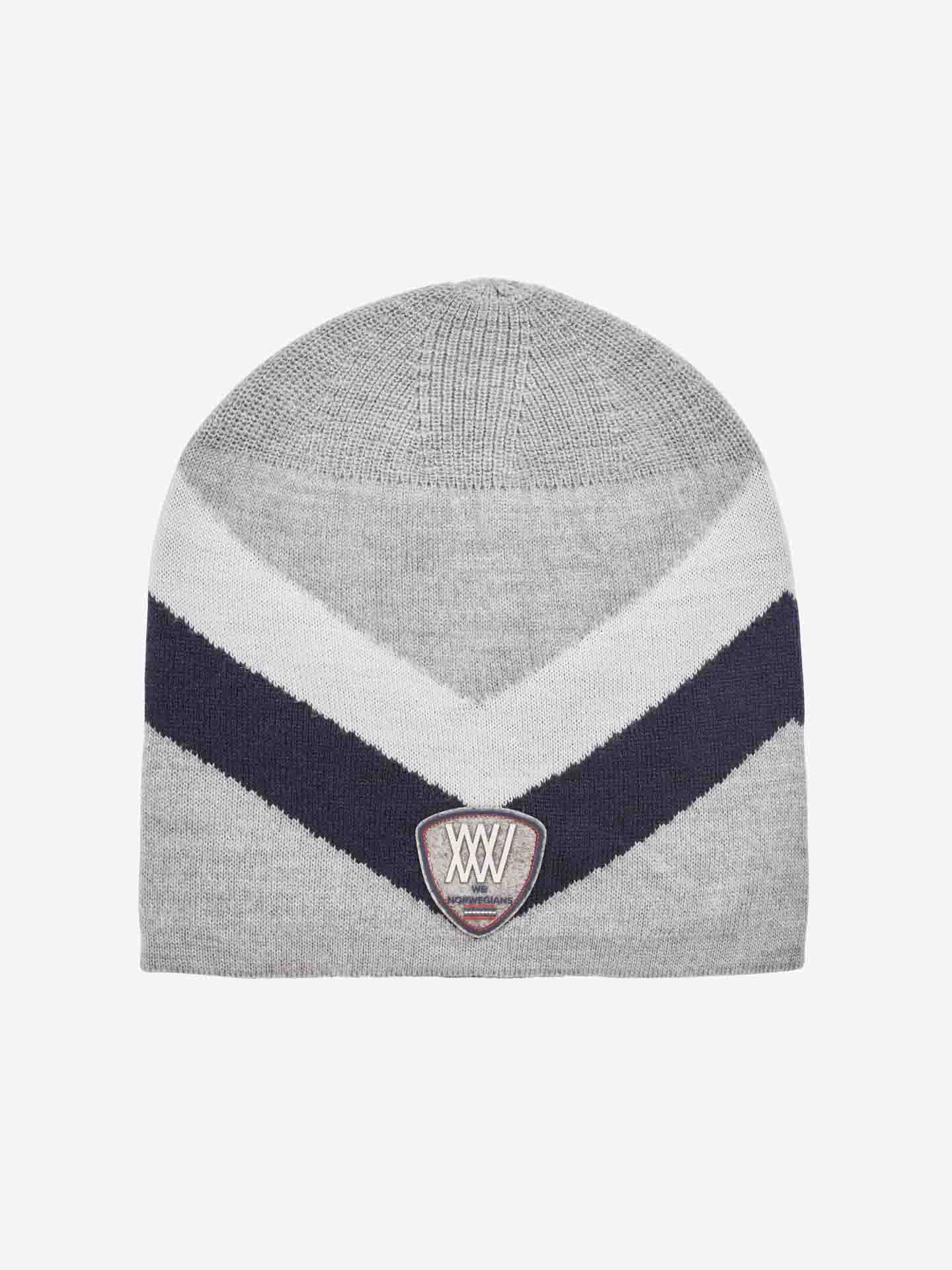 The Beito Hat by We Norwegians is a gray knit beanie made from breathable Merino wool. It features bold diagonal stripes in dark blue and light gray forming a chevron pattern, with a small embroidered patch at the center front displaying "XXV" in white text. The background is plain white, making it an ideal accessory for ski hat enthusiasts.