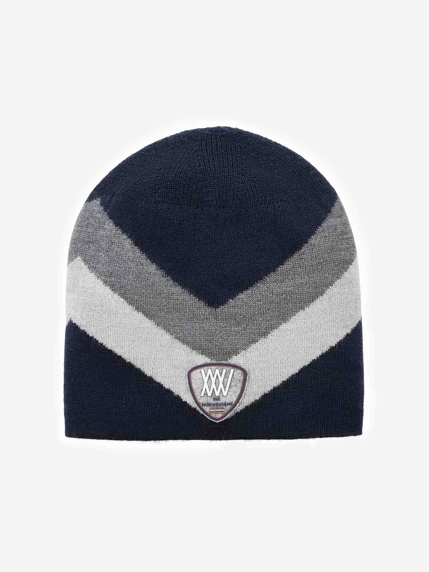 The Beito Hat by We Norwegians is a beanie featuring a dark blue, light gray, and medium gray chevron pattern. Crafted from breathable Merino wool, this ski hat includes a patch centered on the front displaying the letters "XXV" with an emblem underneath.