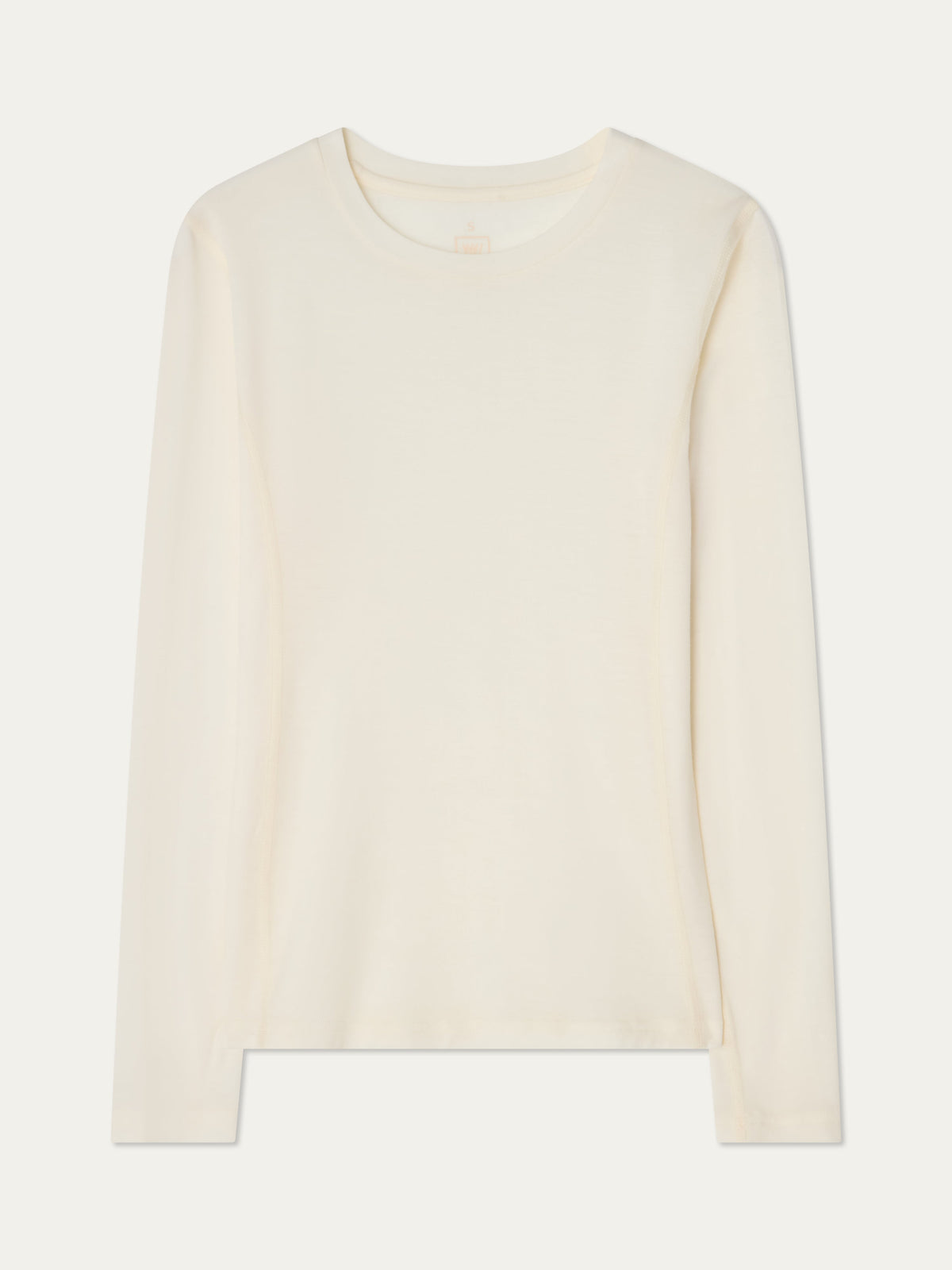 The We Norwegians Sno Merino Crewneck Women is a plain, long-sleeve, off-white merino wool t-shirt laid flat against a white background, crafted from breathable single jersey for a refined and comfortable Scandinavian luxury base layer.