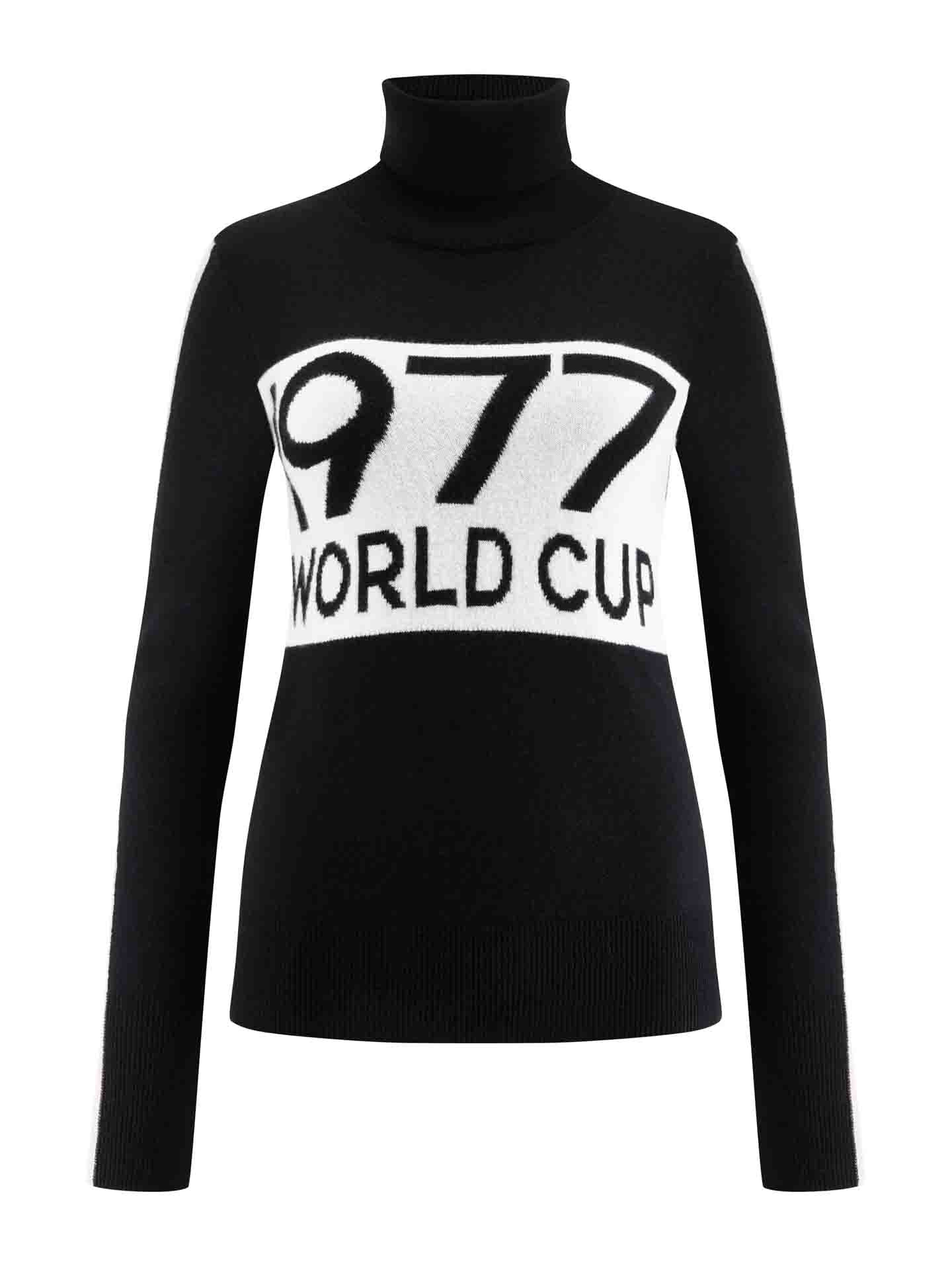 The 1977 World Cup Sweater Women by We Norwegians is a black merino wool turtleneck sweater, featuring a bold white band across the chest with "1977 WORLD CUP" prominently displayed in large black letters. Its long sleeves and fitted silhouette make it an ideal choice for ski fashion enthusiasts.