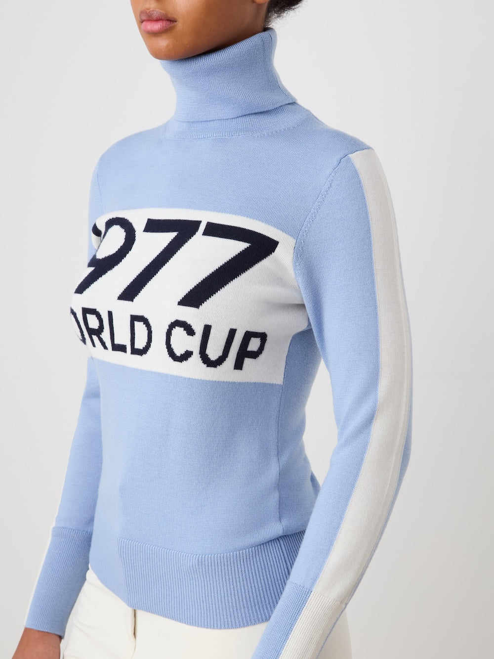 A woman wears the We Norwegians World Cup Sweater women - Pre Spring 26, embracing après-ski style.
