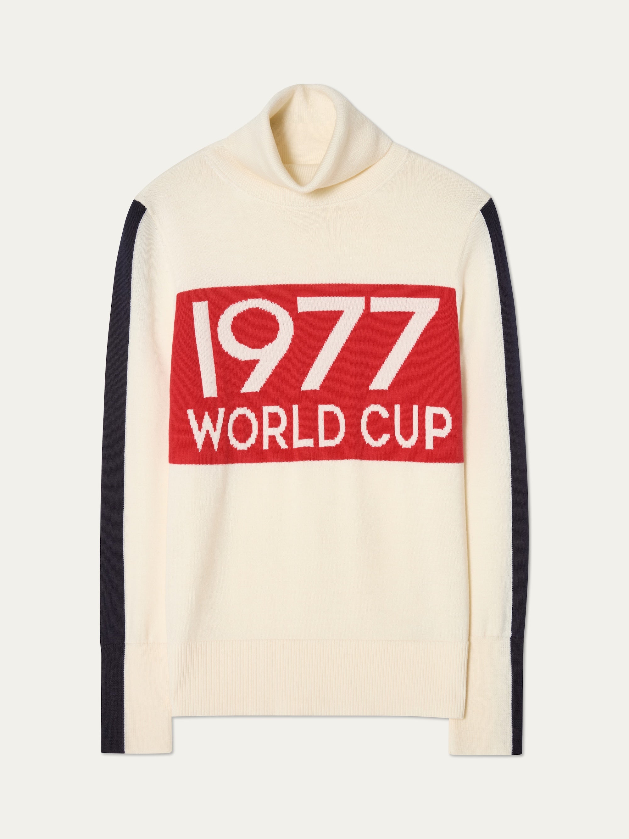 The 1977 World Cup Sweater Women by We Norwegians is a cream ski sweater with black sleeve stripes and a bold red chest rectangle displaying "1977 WORLD CUP" in white—capturing vintage 70’s ski style.