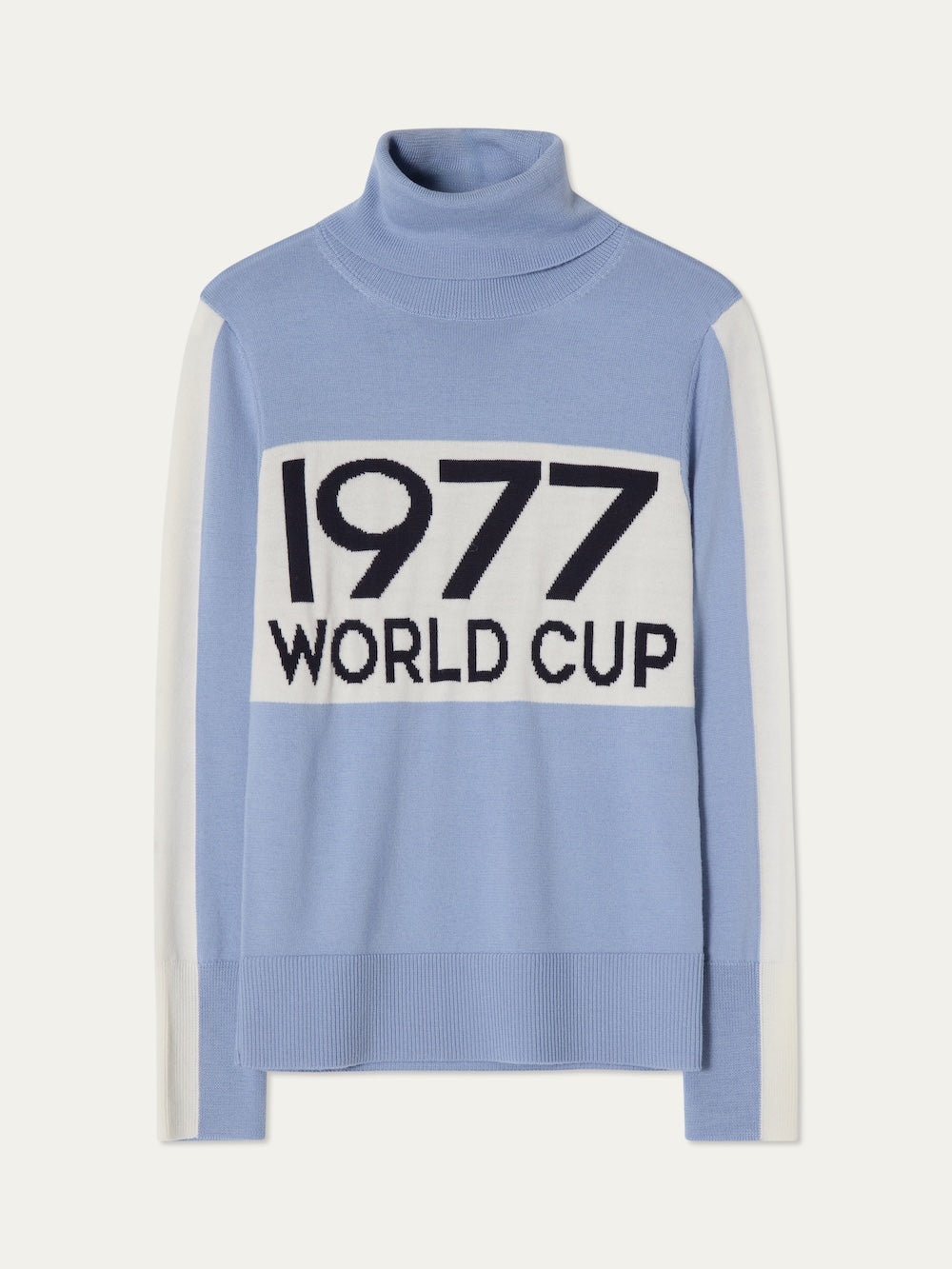 The We Norwegians World Cup Sweater women - Pre Spring 26 is light blue with après-ski style, white sleeve panels, and bold "1977 WORLD CUP" across a white chest block.