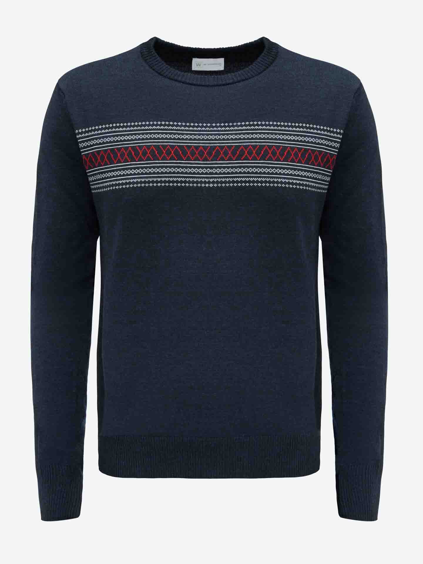 The Signature Crewneck Men from We Norwegians is a dark blue merino wool sweater with a round neck, showcasing a horizontal pattern of white and red geometric designs across the chest. Inspired by Norwegian heritage, this sweater features ribbed cuffs and hem for added warmth.