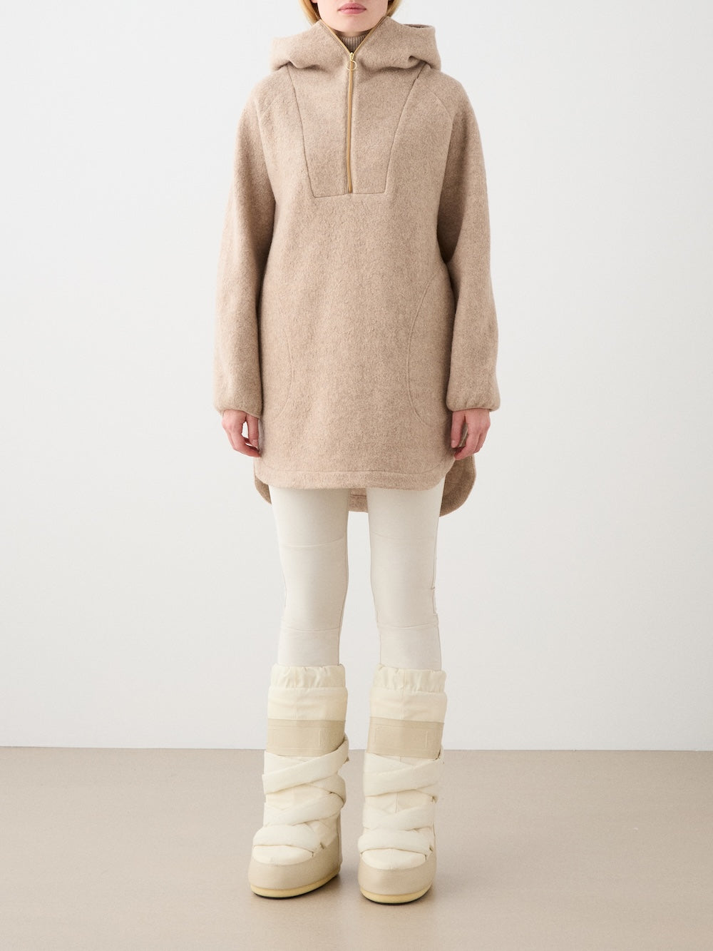 We Norwegians | FW25 | Womens Alta Hoodie_Camel | Person wearing the  hooded sweater and white boots on a plain background | Front