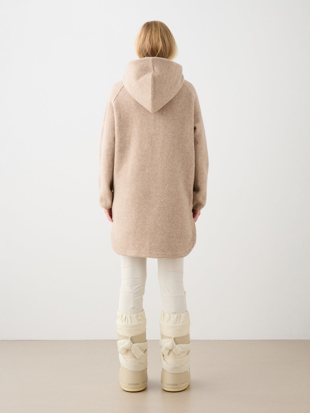 We Norwegians | FW25 | Womens Alta Hoodie_Camel | Person wearing the hooded sweater and white boots on a plain background | Back