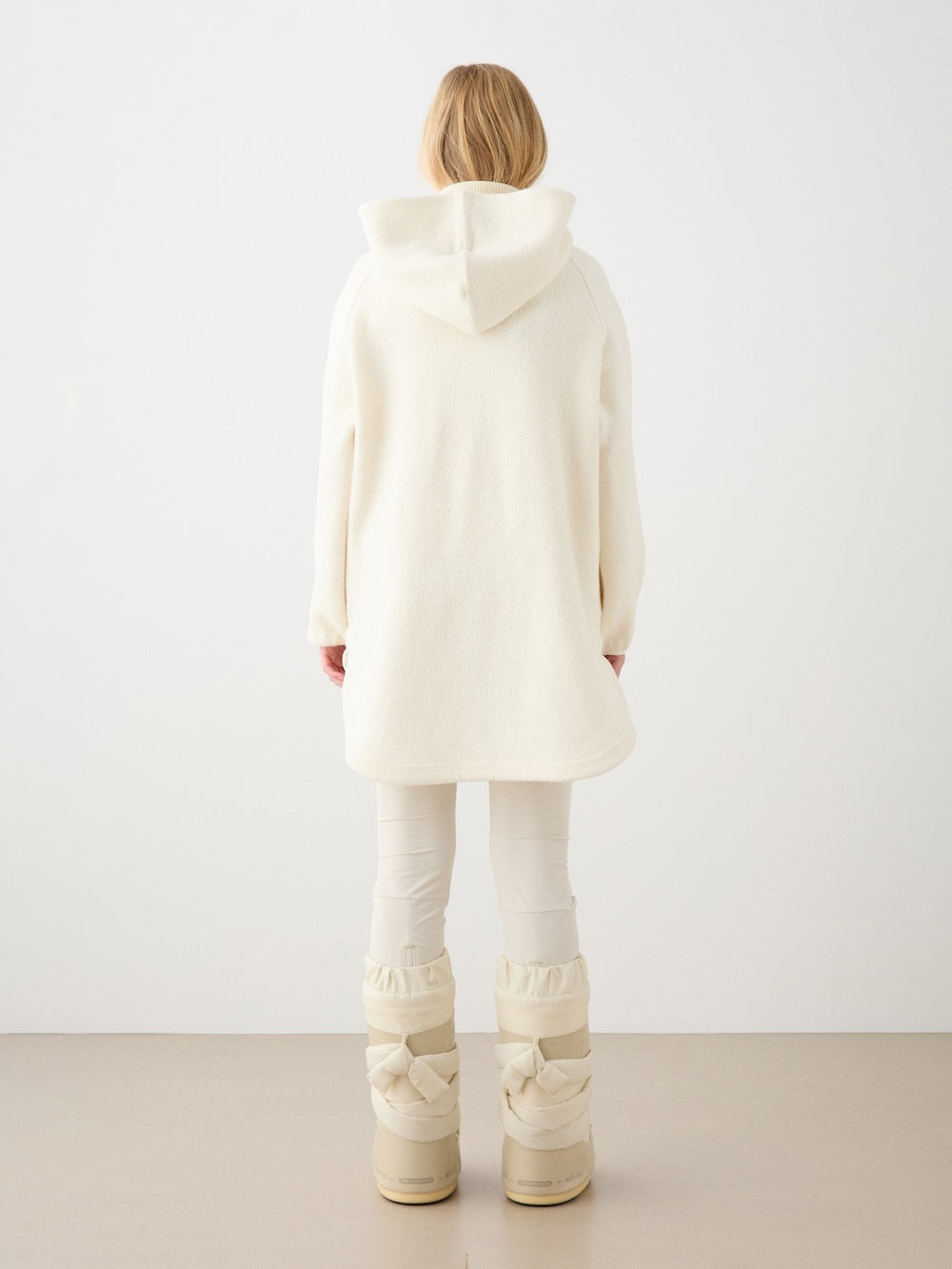 We Norwegians | FW25 | Womens Alta Hoodie_Off white | Person wearing the off-white-colored sweater with a long-sleeve top and pants on a white background | Back