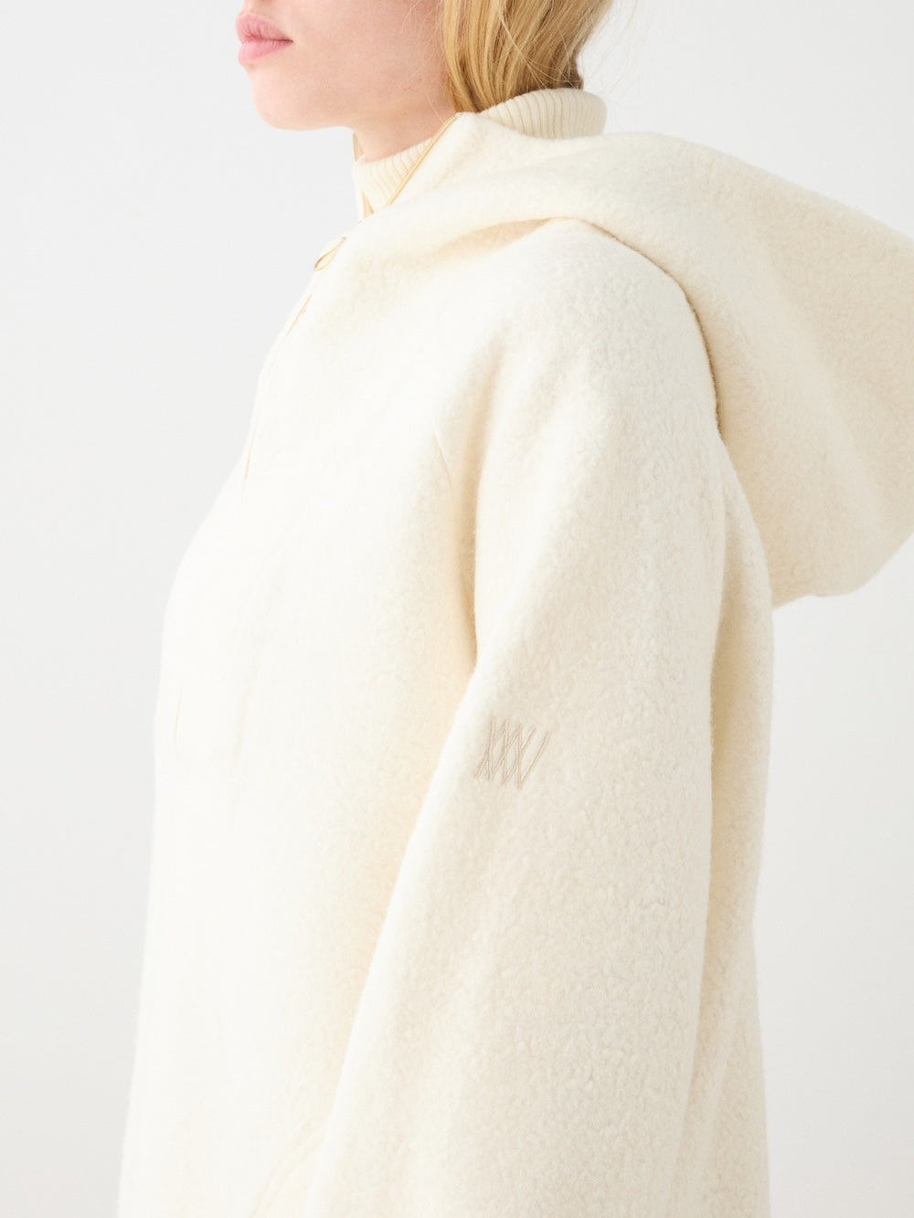 We Norwegians | FW25 | Womens Alta Hoodie_Off white | Person wearing the off-white-colored sweater with a long-sleeve top on a white background | Side/ close-up