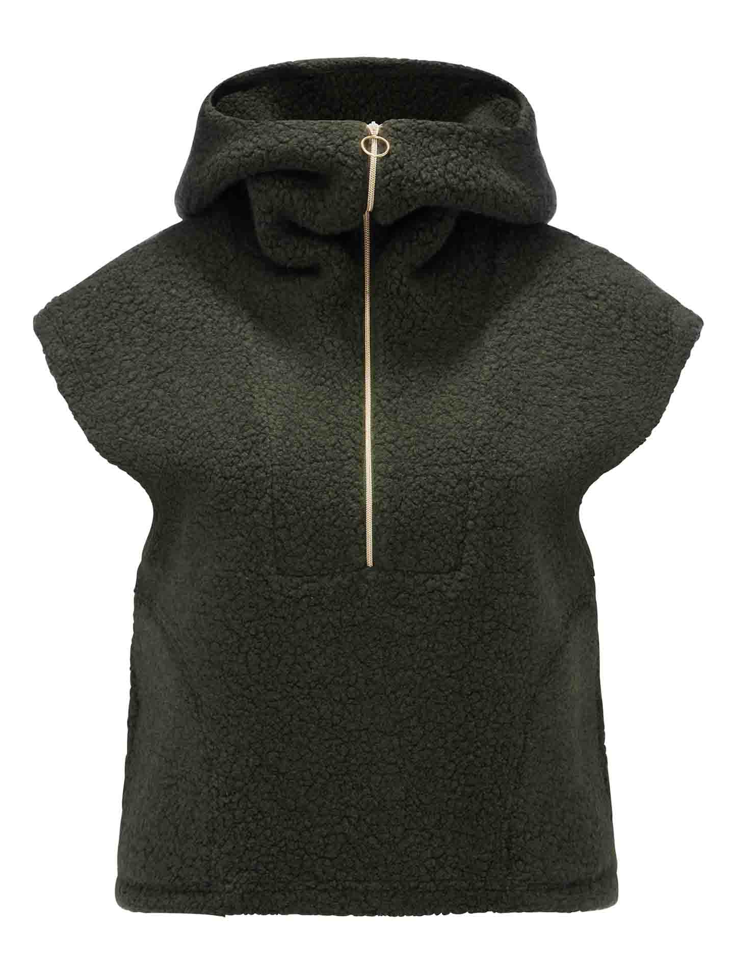 The Alta Hooded Vest Women by We Norwegians is a dark green sleeveless fleece hoodie from the Alta collection, featuring a high neckline with a zippered closure. The zip includes a circular pull tab, and the Merino wool fabric has a textured, cozy appearance.