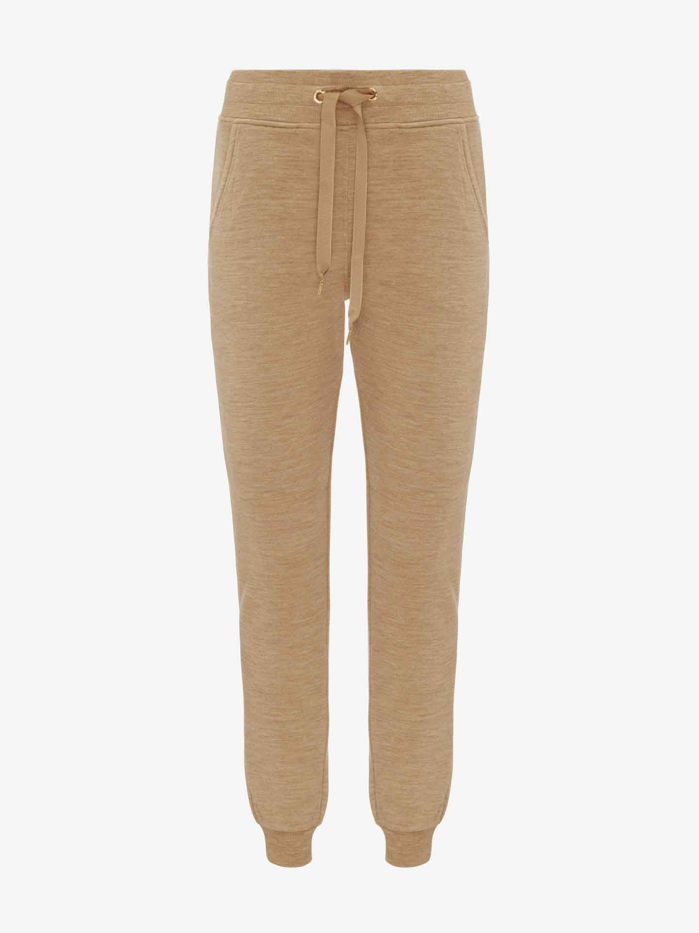 A pair of We Norwegians Tind Jogger Women Camel pants, featuring a structured knit drawstring waist and two front pockets. The Merino wool blend joggers have a relaxed fit and elasticated cuffs at the ankles, set against a white background.