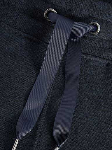 Close-up of the waistband of a pair of Tind Jogger Women Navy pants by We Norwegians, focusing on a tied drawstring. The navy blue, ribbed texture drawstring is looped through metallic eyelets, complementing the relaxed elegant style of these Merino wool sweatpants.