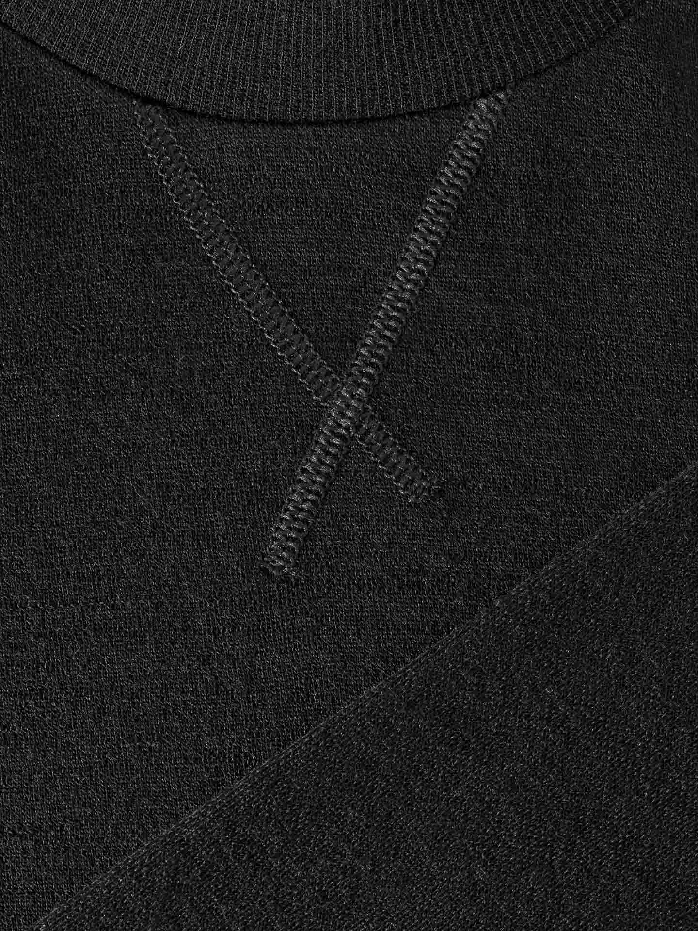 Close-up of the black ribbed fabric on the Tind Crewneck Women Black by We Norwegians, featuring an intersecting stitch pattern. The knit appears textured, likely Merino wool, and is designed for sportswear, showcasing a detailed view of the stitching on this garment.