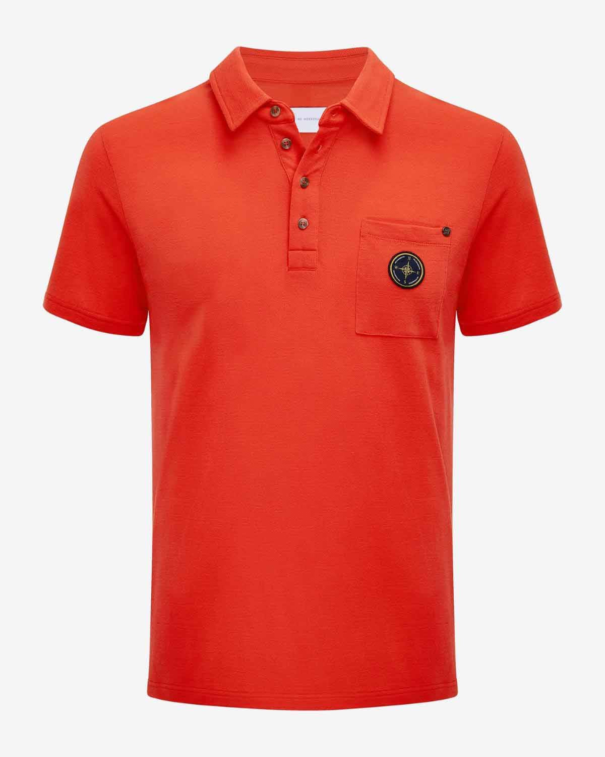 The Lindesnes Polo Men Coral from We Norwegians is a vibrant orange shirt made from Creora-Eco-Soft. It features a collar and button-up neckline, along with a pocket on the left chest, embellished with a round emblem for added style.