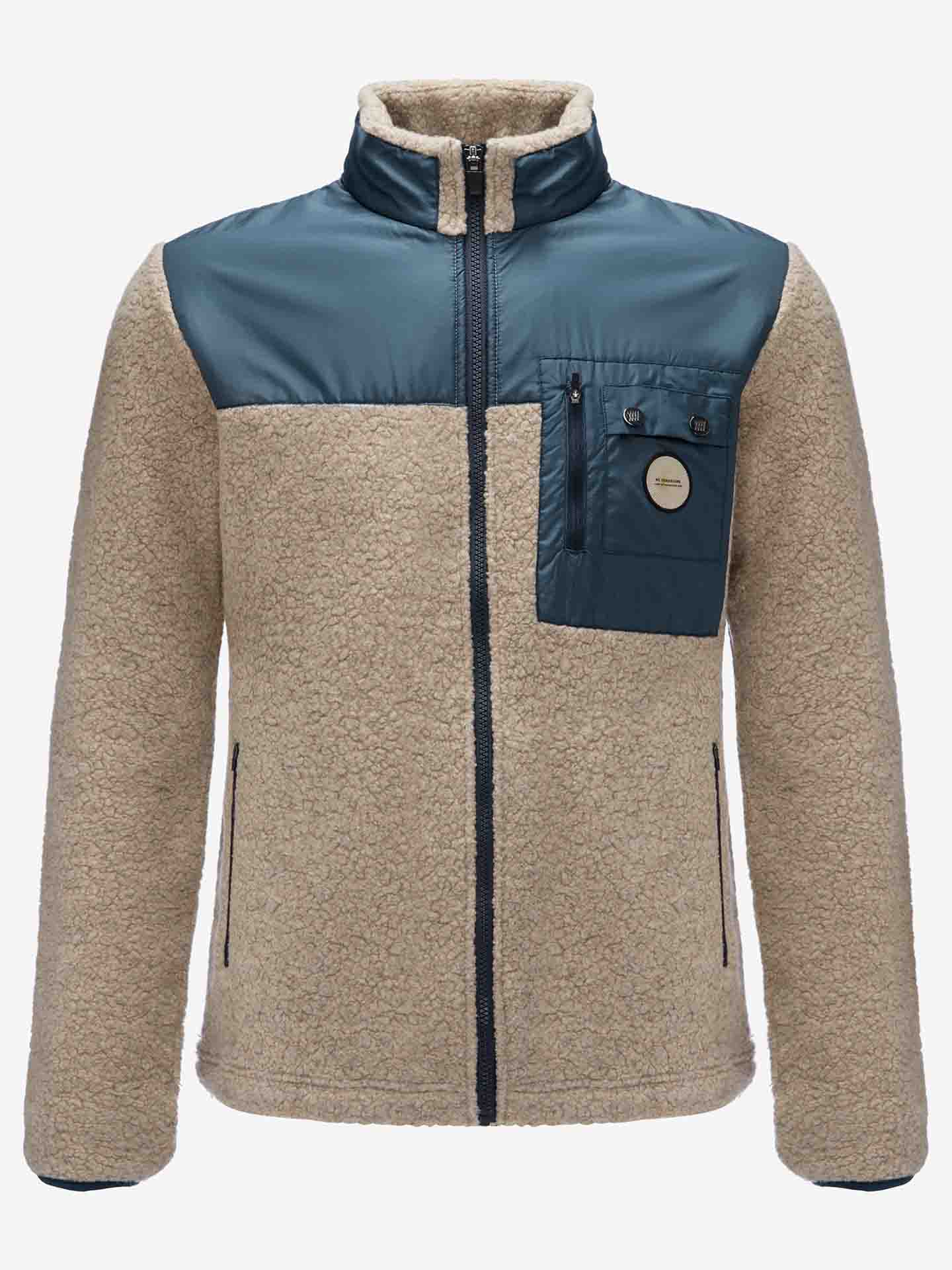 Part of the Alta collection, the We Norwegians Alta Jacket Men is a beige, long-sleeved fleece jacket with a front zipper that’s perfect for outdoor activities. It features contrasting dark green panels on the upper chest and collar, a zippered chest pocket with button details, and a circular patch bearing a small inscription.