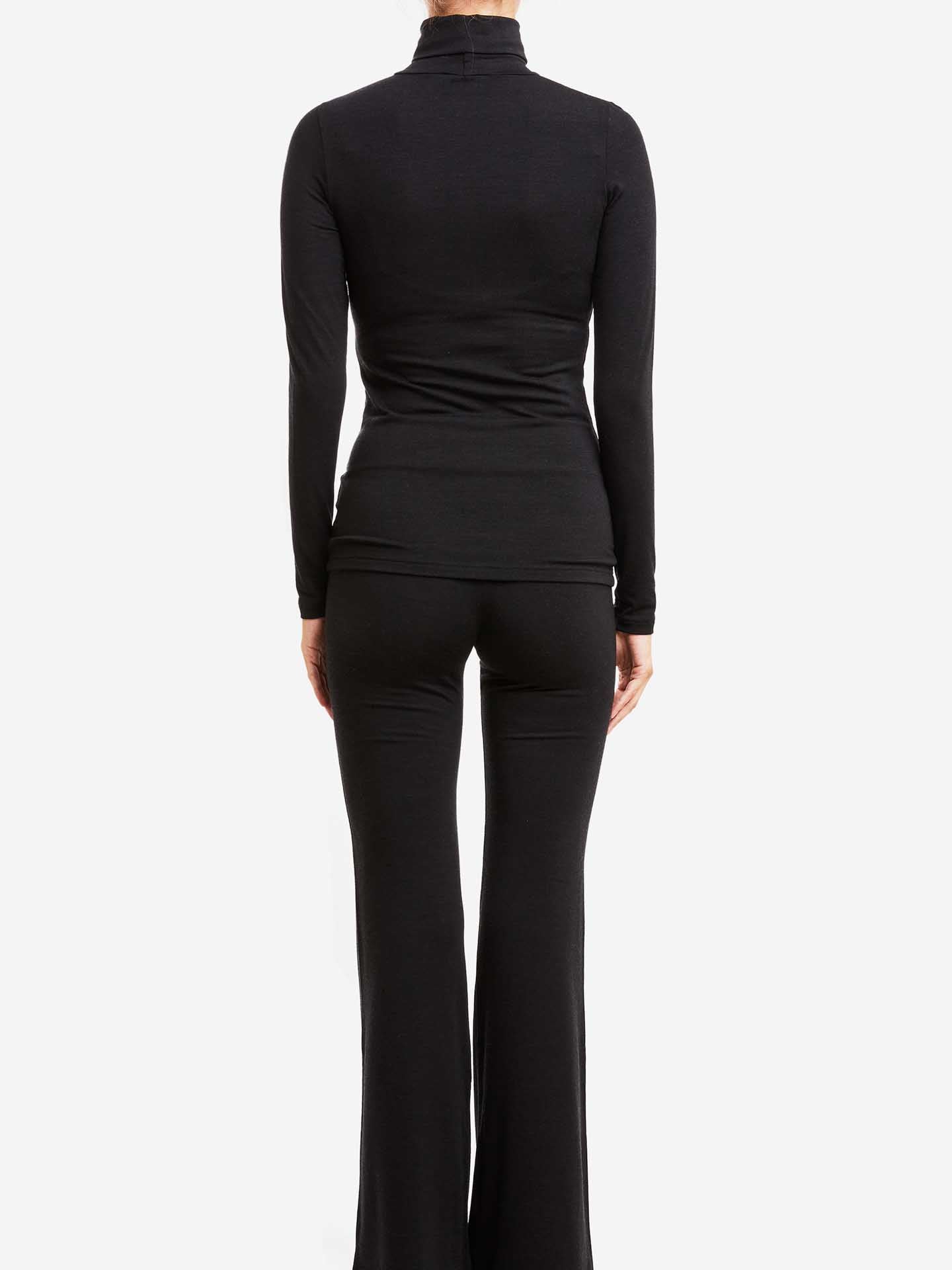 A person is shown from the back, wearing a long-sleeve black Hygge Turtleneck Women by We Norwegians and black flared pants. The form-fitting outfit, made from merino wool and Tencel, exudes comfort and style against the plain white background.