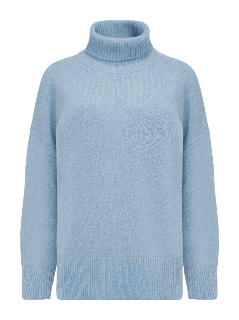 The Blefjell Sweater Women by We Norwegians is a light blue cashmere turtleneck with long sleeves. The sweater features a ribbed collar, cuffs, and hem, offering a cozy, casual look with an oversized fit that exudes luxury.