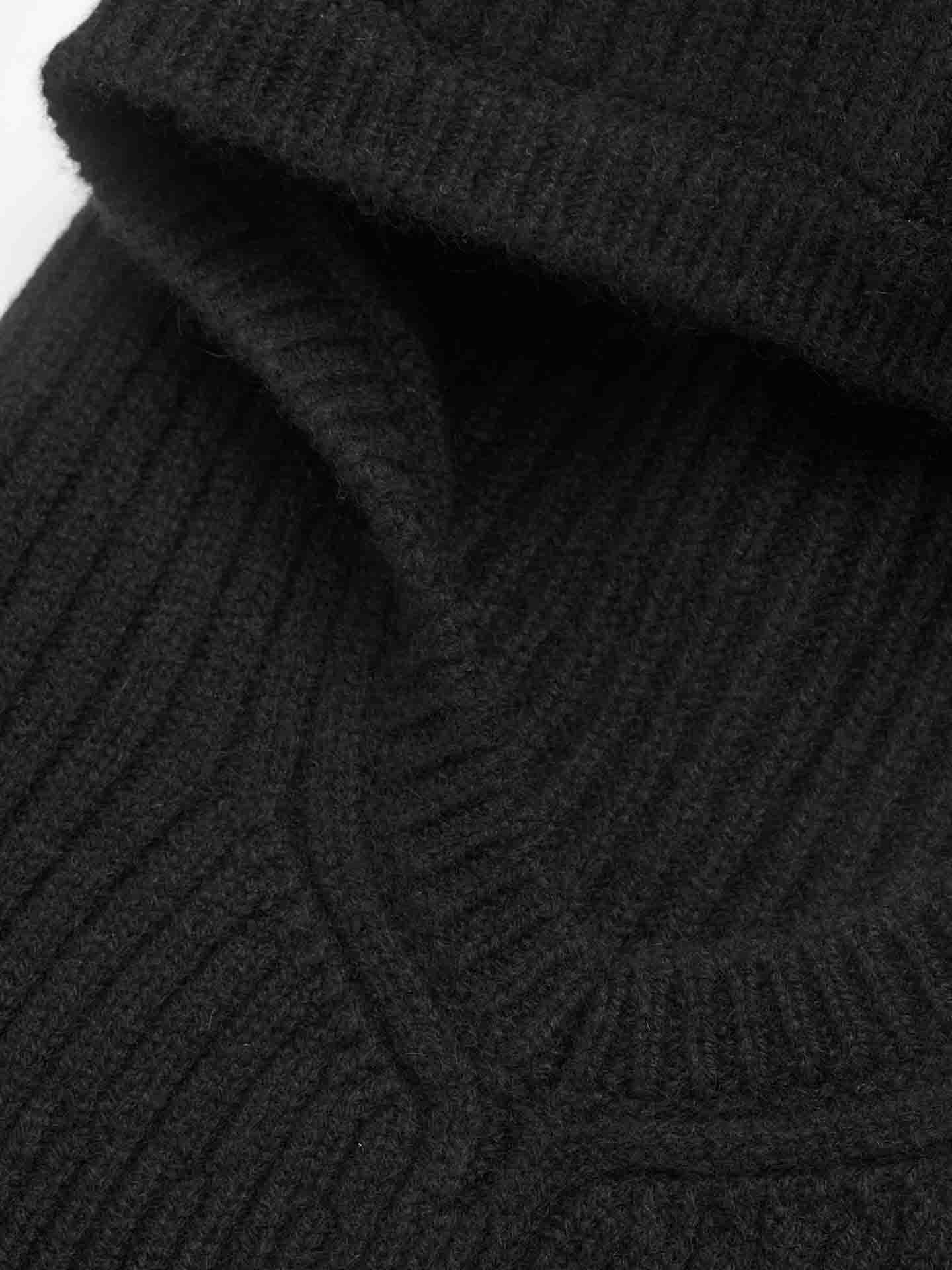 A close-up view of a black ribbed knit fabric from the Blefjell Balaclava Women by We Norwegians. The texture of the material is visible, showcasing the parallel lines and soft, slightly fuzzy surface, indicative of an exquisite cashmere balaclava or similar knitted garment.