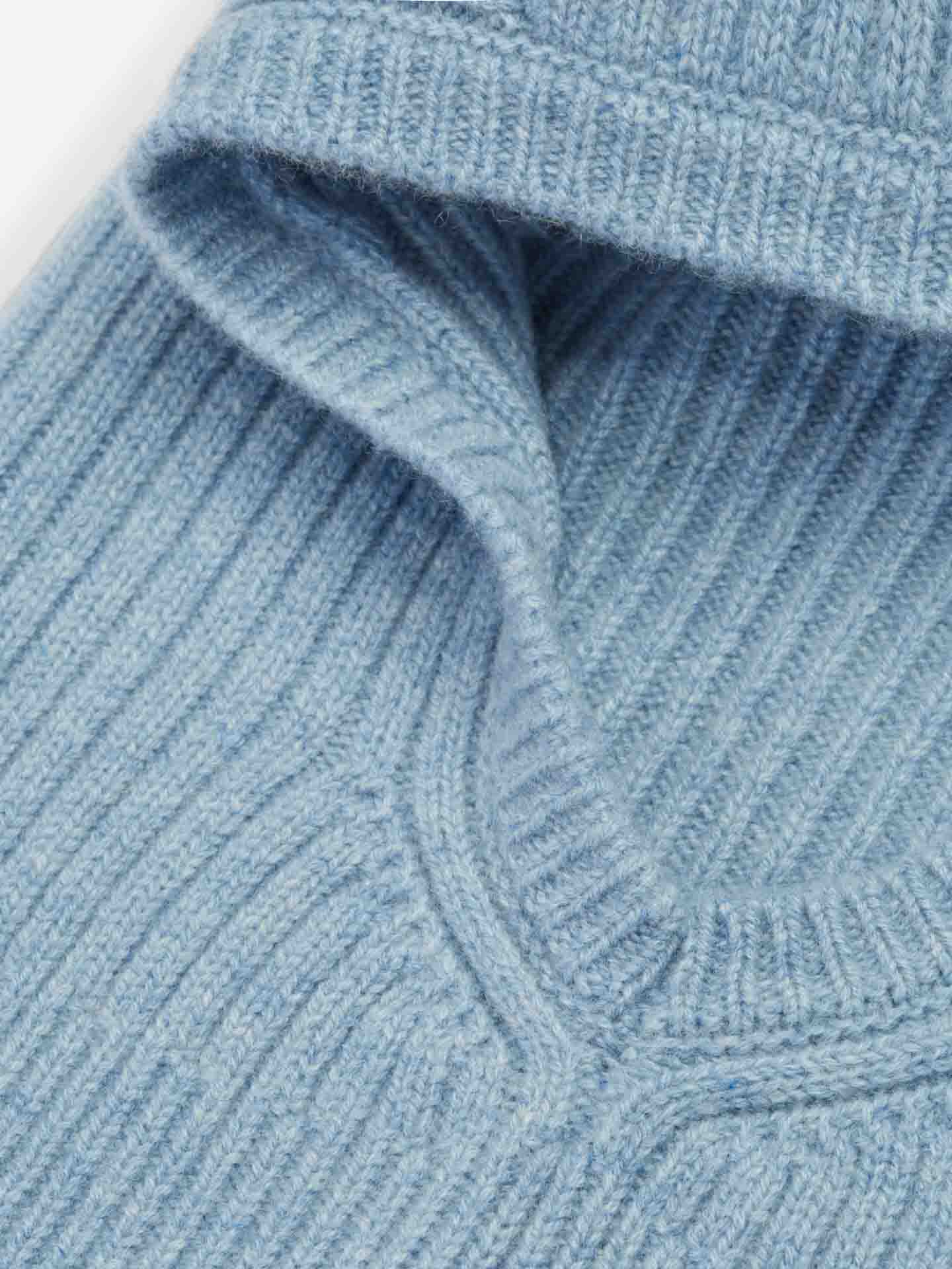 Close-up of a folded Blefjell Balaclava Women by We Norwegians in light blue, ribbed knit fabric. The texture of the knitting and the soft material are clearly visible, showcasing detailed stitching in 1/2 cardigan stitch and the garment's cozy cashmere appearance.