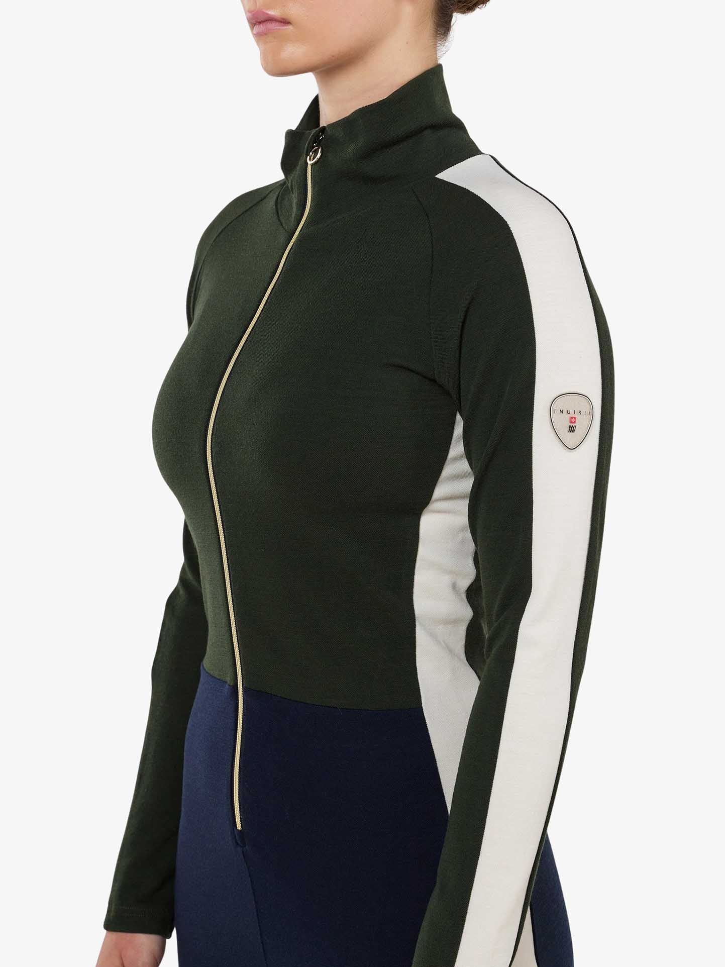 Dressed in the We Norwegians INUIKII + WN Jumpsuit Women, one embodies the ultimate ski fashionista style. This jumpsuit, featuring a dark green body with white side panels and a high collar, is adorned with a crest logo on the sleeve. It's perfect for making a seamless transition from skiing to après-ski while posing sideways against a plain backdrop.