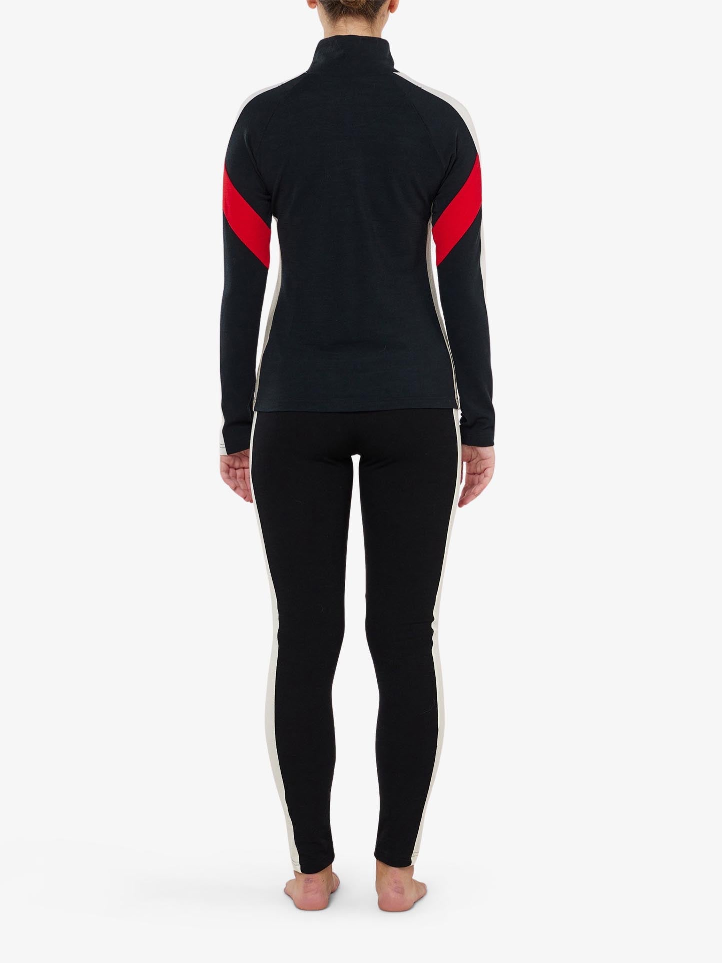 A rear view displays a person standing barefoot in We Norwegians' Inuikii+WN Leggings for Women, featuring a sleek design with white and red stripes. The top has long sleeves, and the wool leggings showcase stylish side stripes, echoing ski fashion against a plain white background.