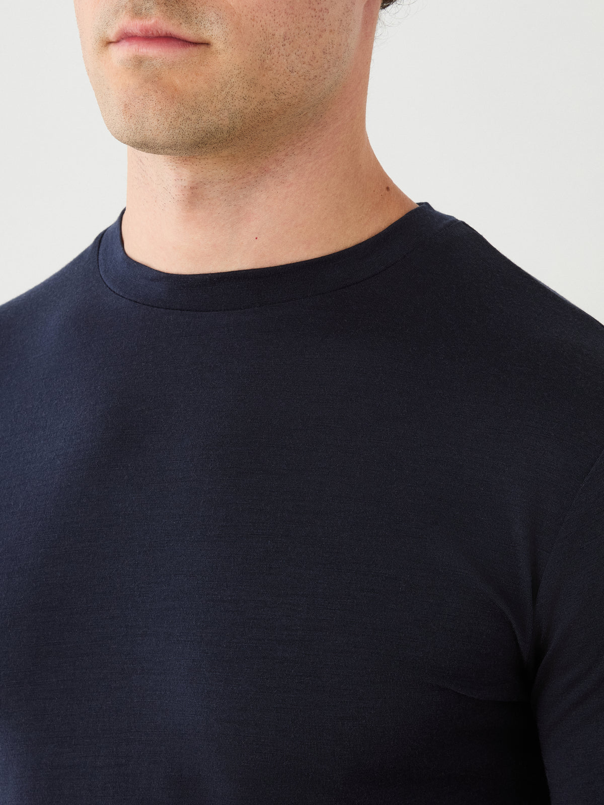 A close-up of a person wearing the Sno Merino Long Sleeve Men by We Norwegians. Only the lower face, neck, and upper torso are visible against a plain light background.