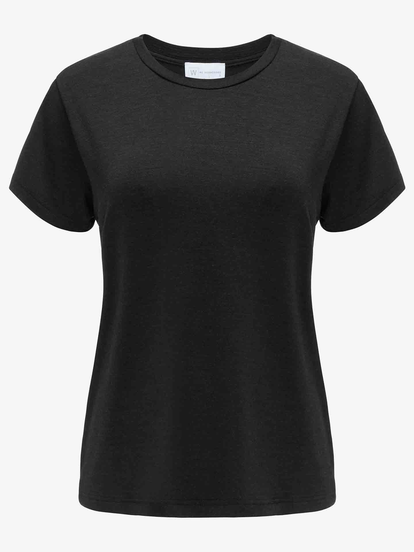 The Hygge Tee Women by We Norwegians is displayed on a white background. This plain black short-sleeve T-shirt, made from merino wool, features a crew neckline and straight cut, exuding simplicity and casual elegance. A small tag near the neckline adds to its appeal as a luxury base layer.