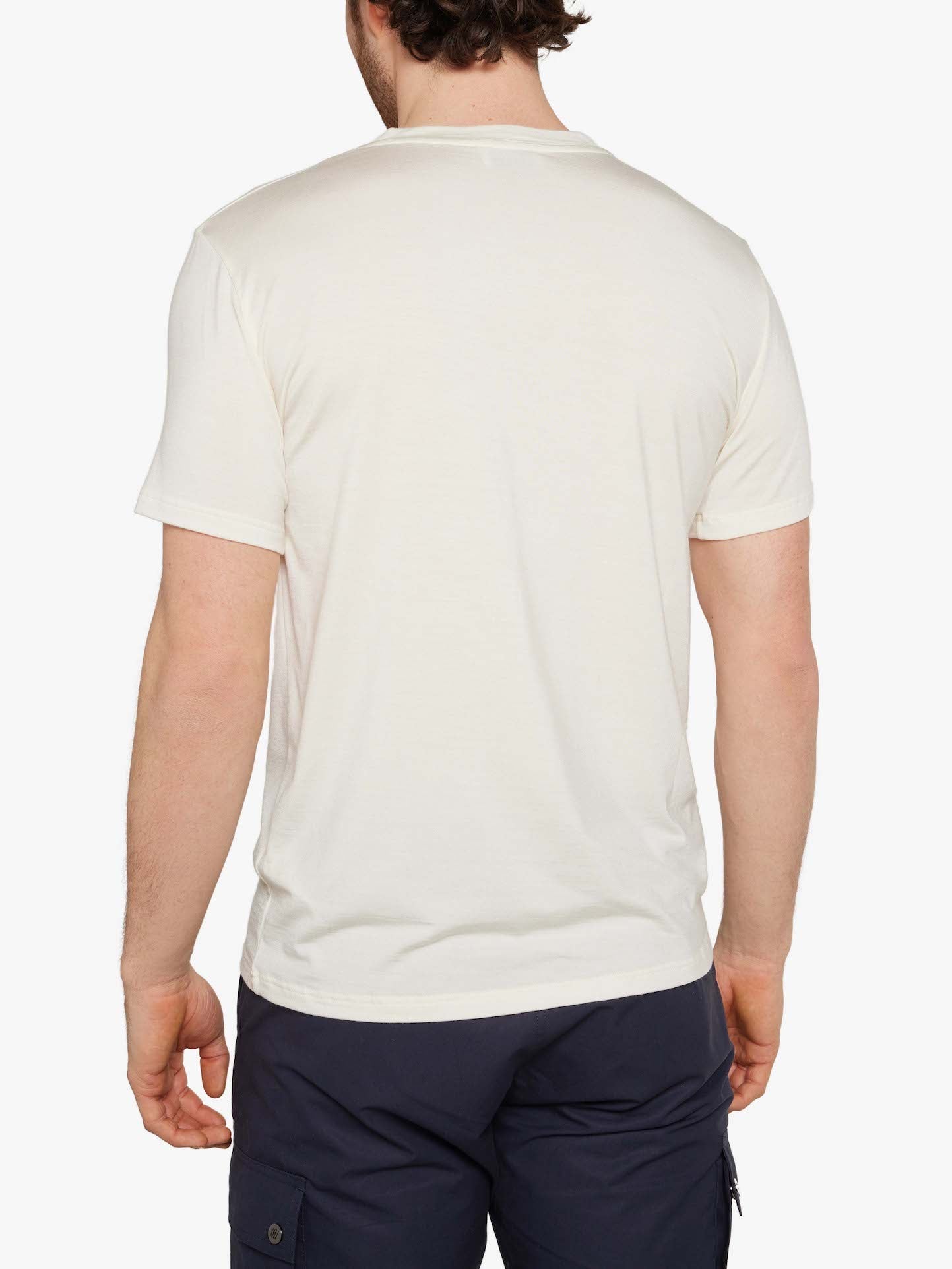 Rear view of a person with short dark hair wearing a plain white Hygge Tee Men from We Norwegians and dark blue pants. The person is standing against a white background.