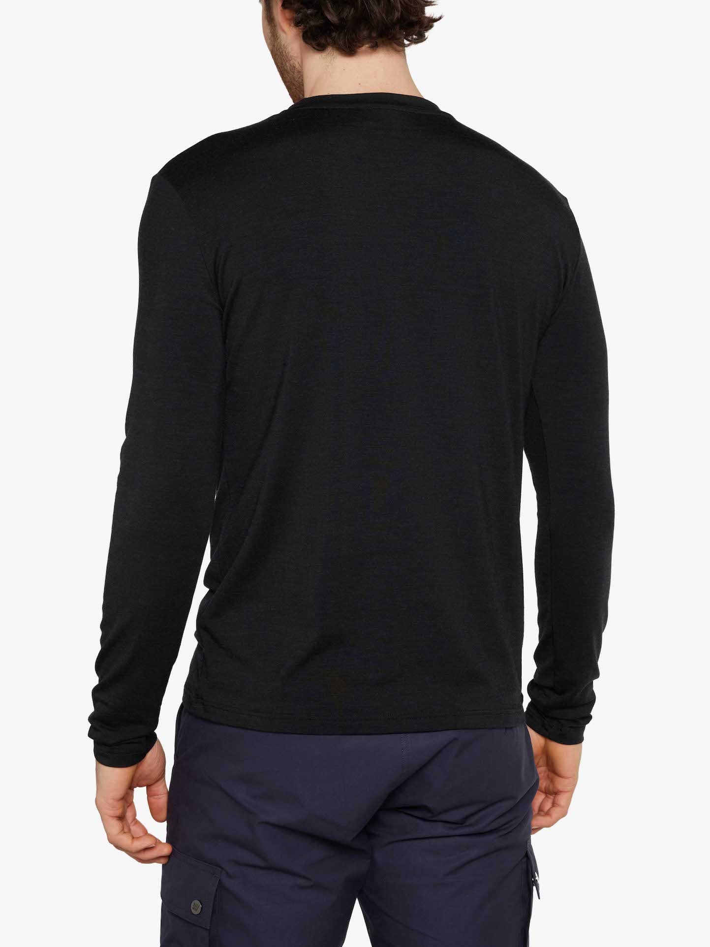 Rear view of a person wearing a We Norwegians Hygge LongSleeve Men shirt in black and navy cargo pants. The person is standing with their arms relaxed by their sides, against a plain, light-colored background.