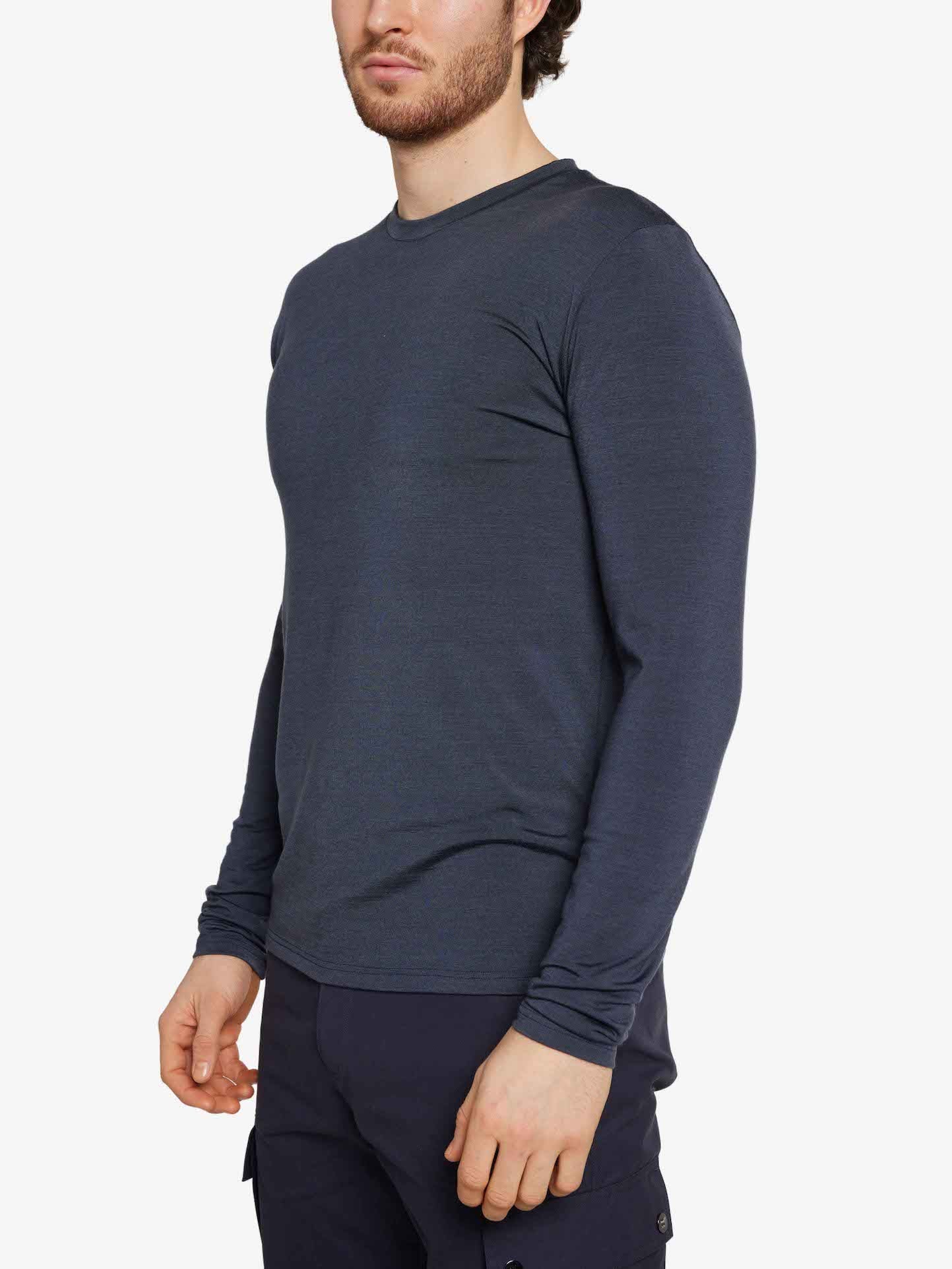 A person is wearing a fitted, long-sleeved Hygge LongSleeve Men shirt and matching dark blue pants from We Norwegians. They stand with their left hand partially visible and their right hand relaxed by their side, evoking a sense of Hygge against the plain white background.