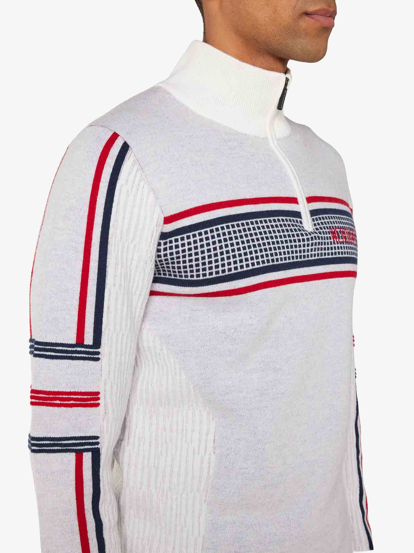 A person is wearing a We Norwegians Stryn Zipup Men sweater in light gray, crafted from ultrafine merino wool, featuring white, red, and navy blue horizontal stripes on the chest and arms. The high-collared retro ski sweater highlights their side profile, showing only the neck and part of the face.