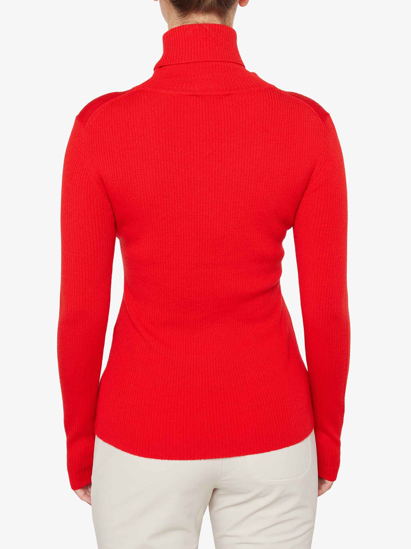 A person is wearing a bright red, long-sleeved Signature Rollneck Women top by We Norwegians. The view is from the back, highlighting the ribbed texture of this fitted roll neck sweater made from fine Merino wool. The outfit is paired with light-colored pants against a plain white background, evoking a hint of retro ski outfits.