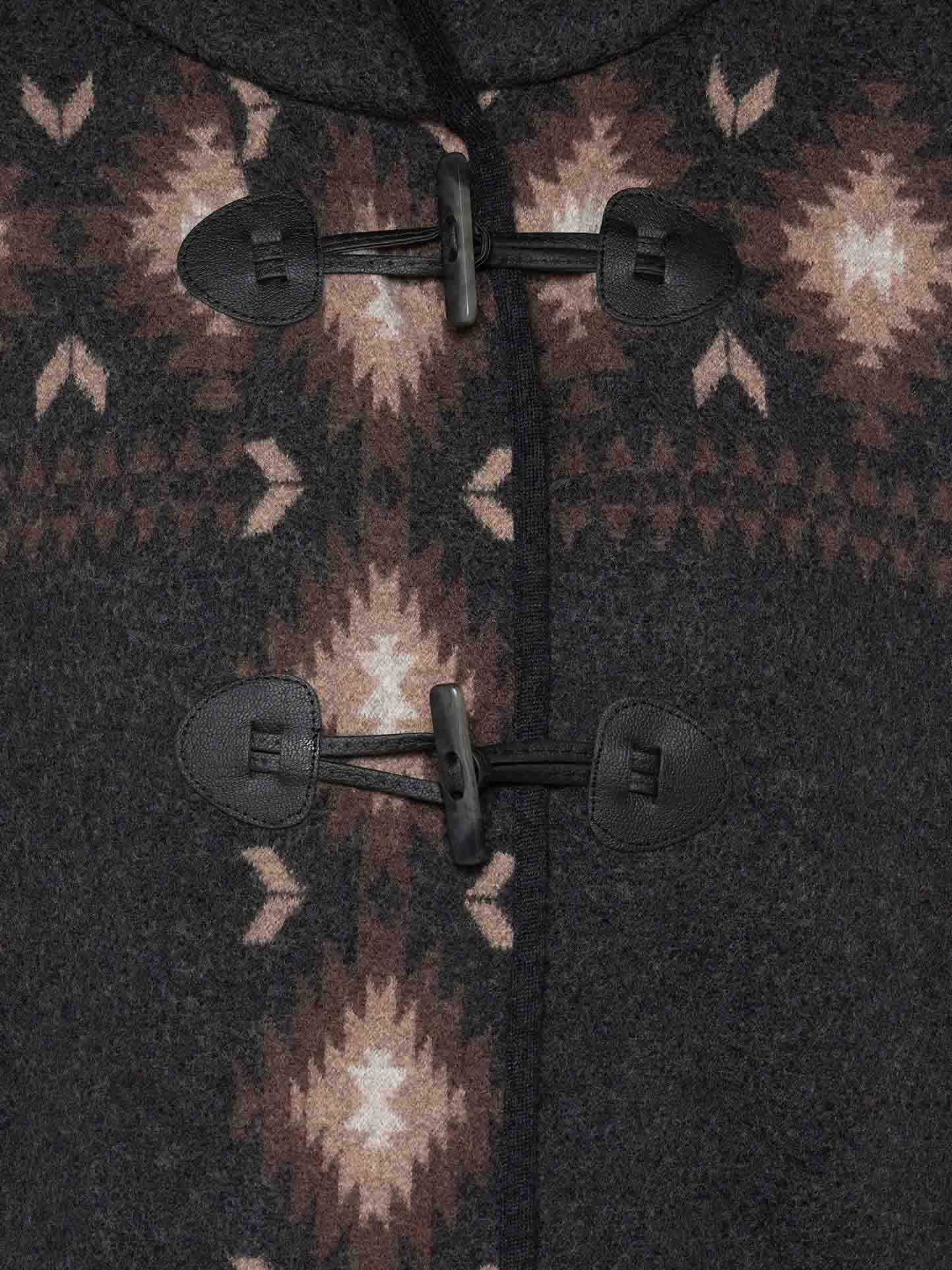 Close-up of the We Norwegians Hovden Jacket Women in gray Merino wool with toggle button closure. Ideal for an Apres Ski look, the jacket features a geometric star pattern in light and dark brown near the buttons. Black toggles with leather fastenings add a rustic touch to this boiled wool garment's design.