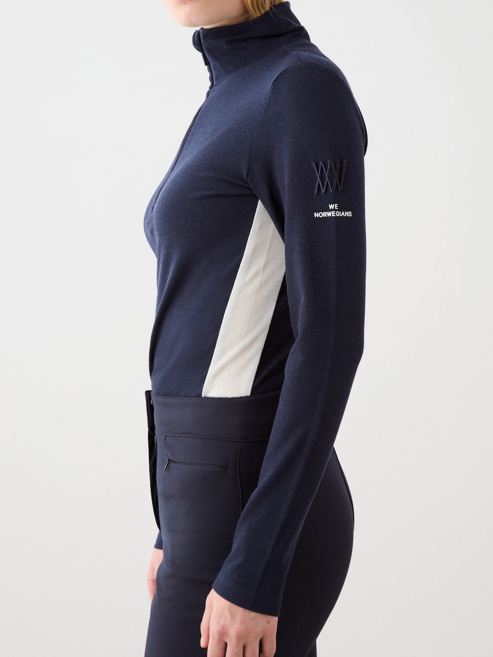 We Norwegians | FW25 | Womens Voss 1/4-Zip_Navy blue | Model is wearing this light knit top with a stand collar, 1/4th zipper opening and long sleeves - paired with black pants on an off-white background | Close-up