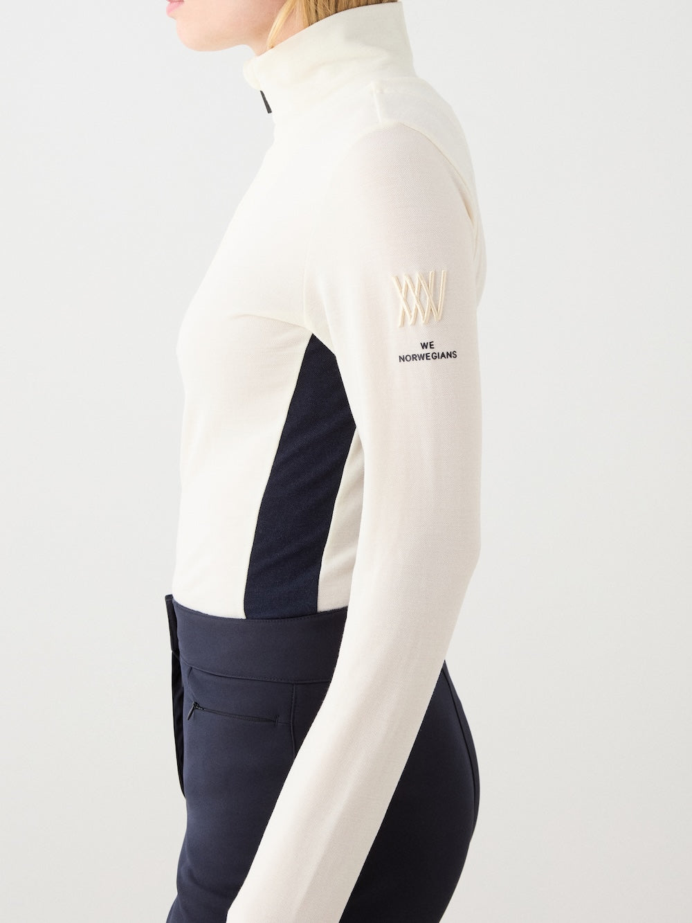 We Norwegians | FW25 | Womens Voss 1/4-Zip_Off white | Model is wearing this light knit top with a stand collar, 1/4th zipper opening and long sleeves - paired with black pants on an off-white background | Close-up