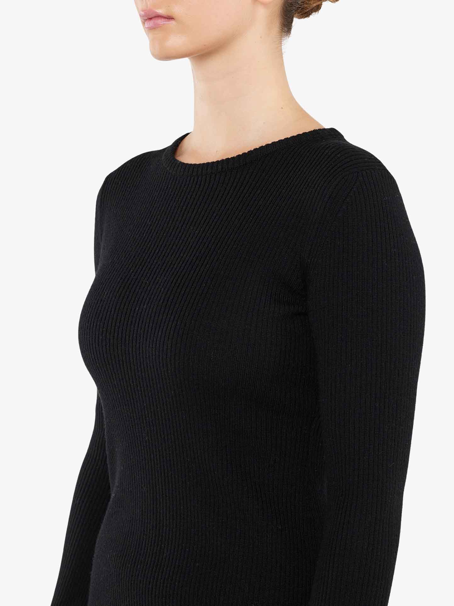 A person's torso and neck are shown wearing the black, long-sleeved Geilo Ribbed Sweater Women, crafted from luxurious merino wool by We Norwegians. The background is plain white, and the individual is positioned in a three-quarter profile, facing slightly to the left.