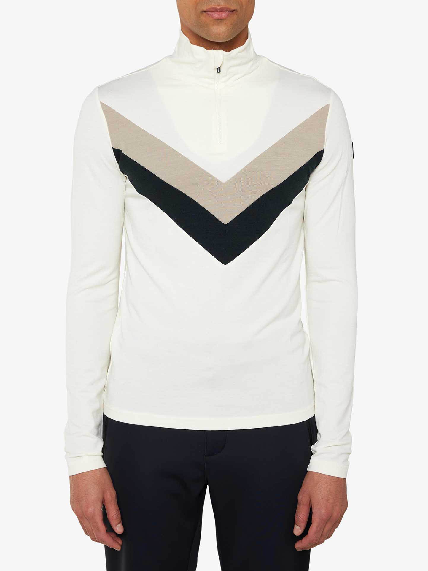 A person wearing the We Norwegians Voss Chevron Zipup Men pullover, featuring a beige and black chevron design and crafted from superfine Merino wool for a retro look, stands against a plain white background, dressed in dark pants.