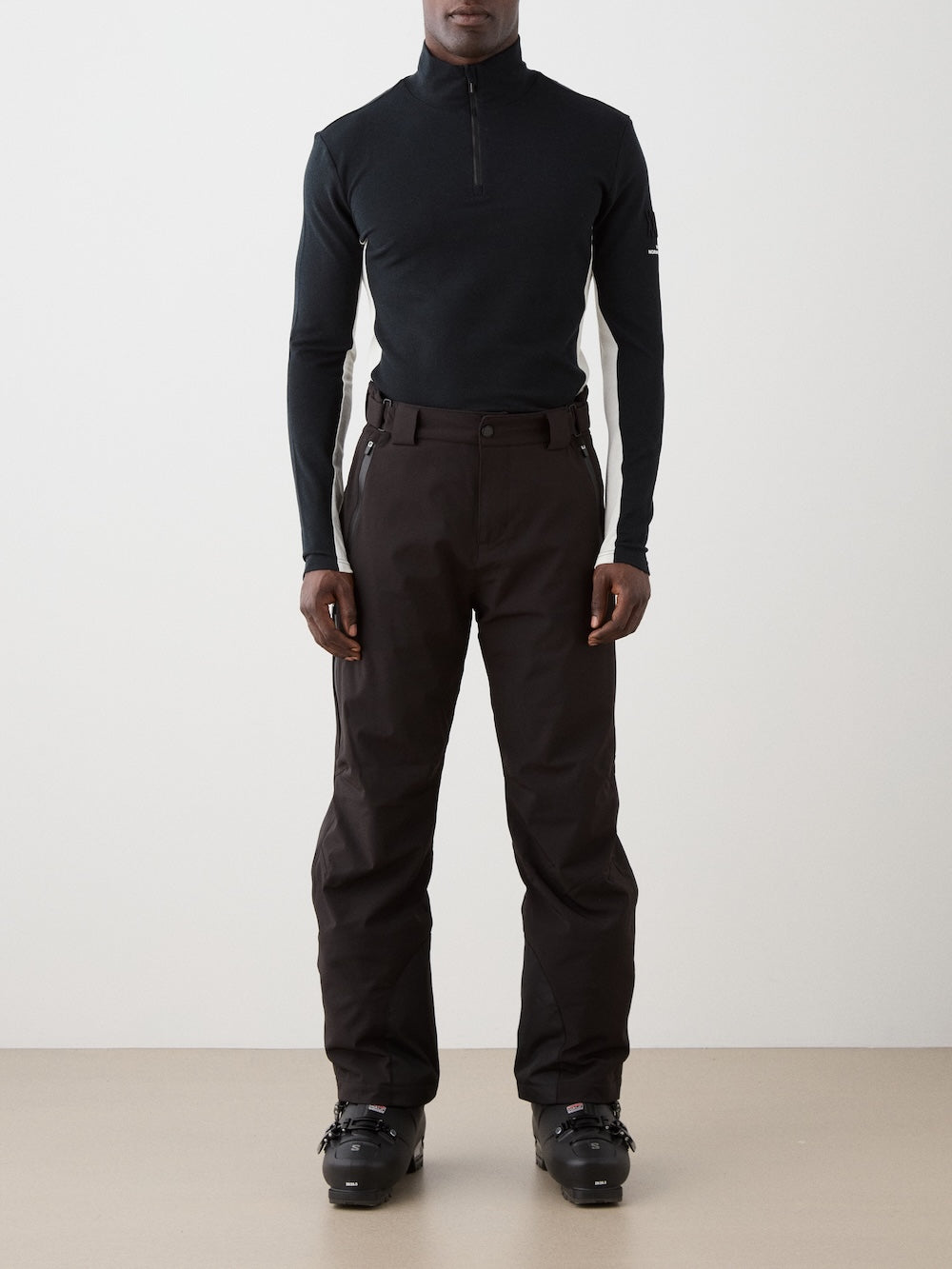 We Norwegians | FW25 | Mens Voss 1/4-Zip_Black | Model is wearing this light weight knitted top with a stand collare, 1/4th zipper opening and long sleeves - paired with black pants on an off-white background | Front