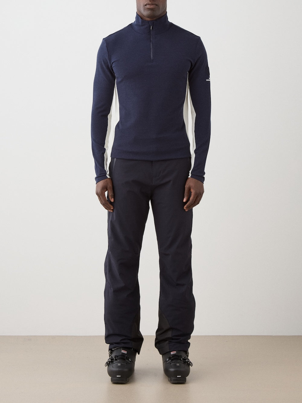 We Norwegians | FW25 | Mens Voss 1/4-Zip_Navy blue | Model is wearing this light weight knitted top with a stand collare, 1/4th zipper opening and long sleeves - paired with black pants on an off-white background | Front