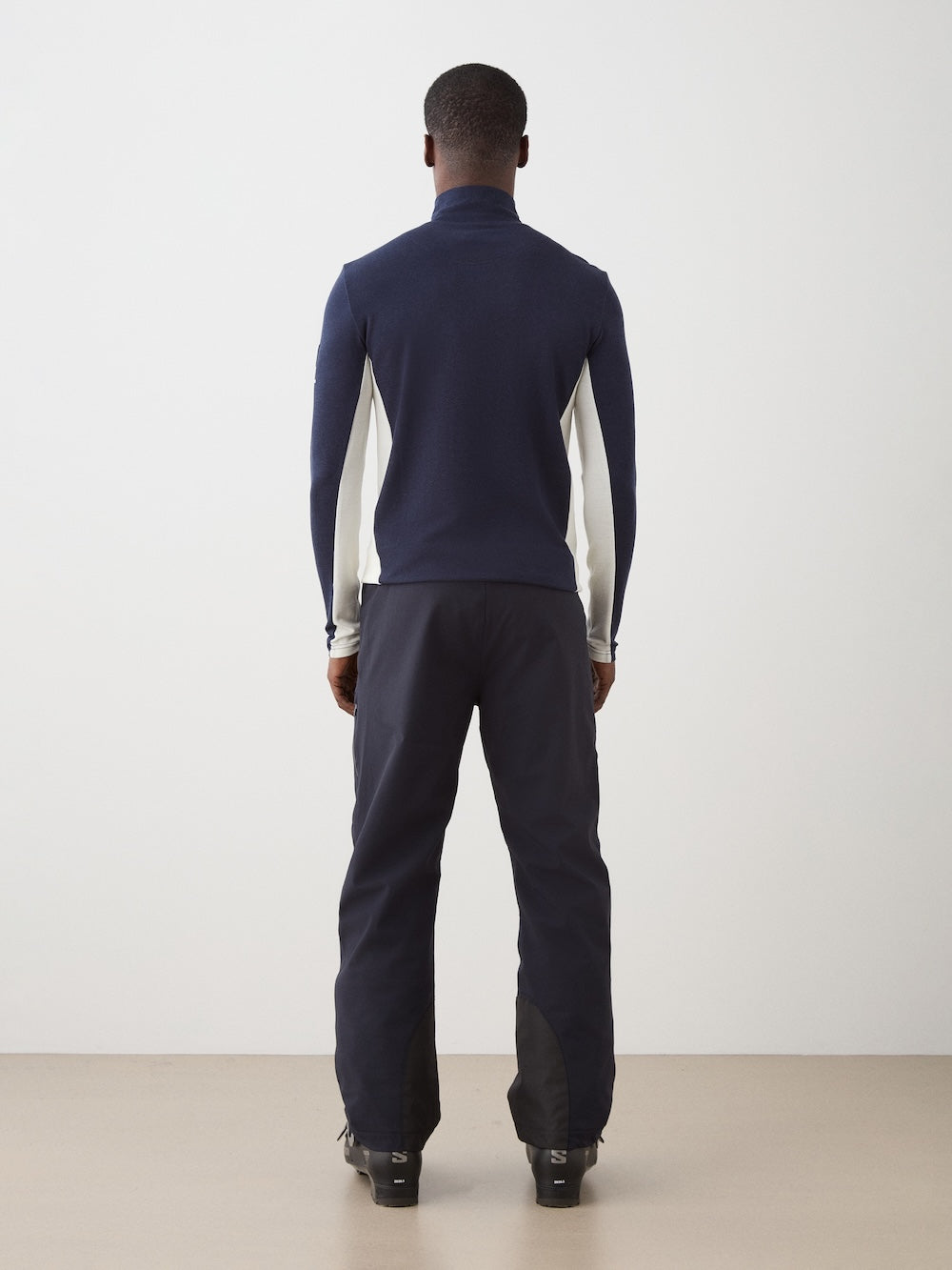 We Norwegians | FW25 | Mens Voss 1/4-Zip_Navy blue | Model is wearing this light weight knitted top with a stand collare, 1/4th zipper opening and long sleeves - paired with black pants on an off-white background | Back