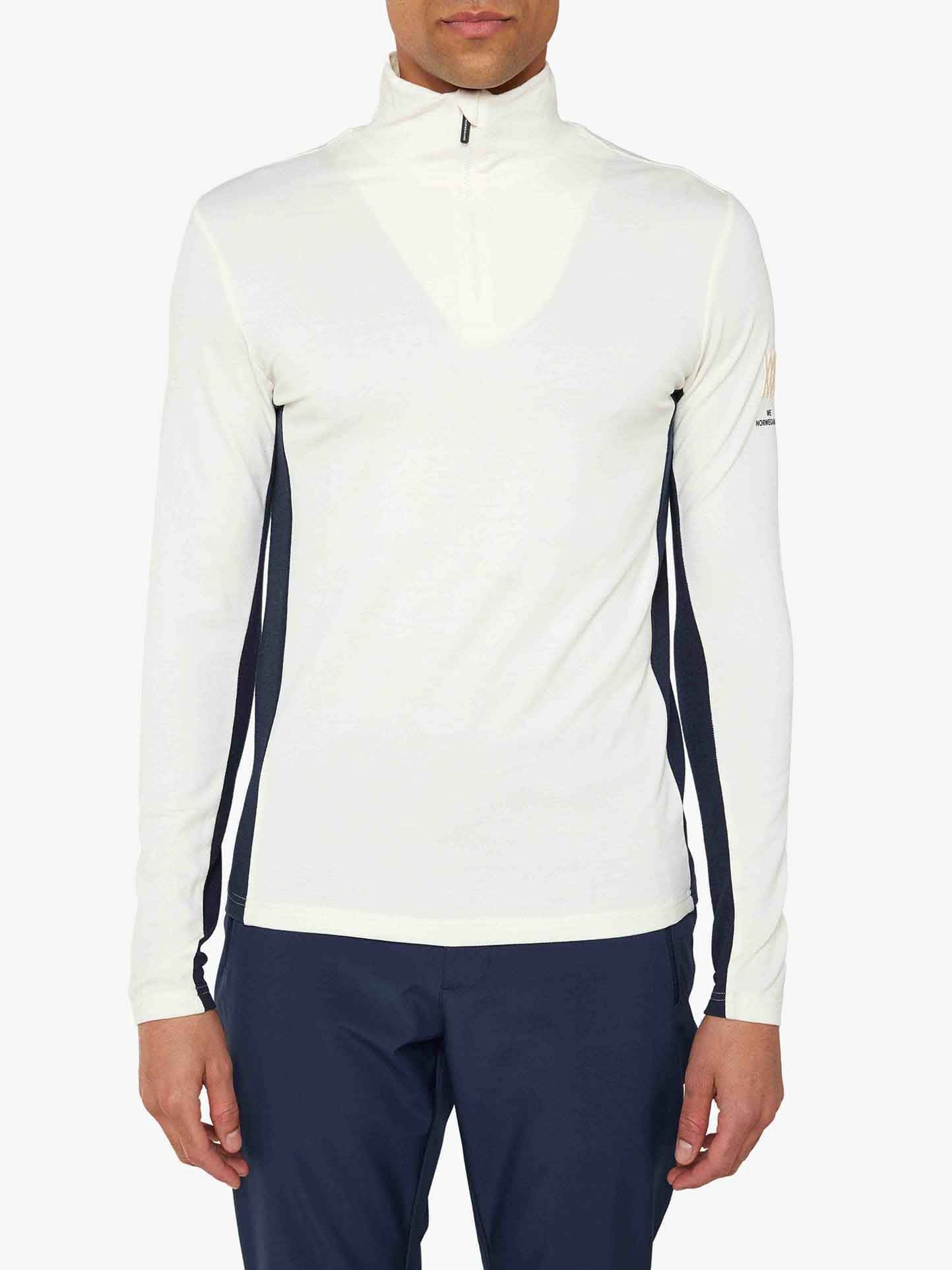 A person is wearing a white Voss 1/4-Zip Men athletic top from We Norwegians, featuring color block panels and dark stripes along the sleeves. The individual has straight dark hair and is facing forward. They are also wearing navy blue athletic pants. The background is plain white.