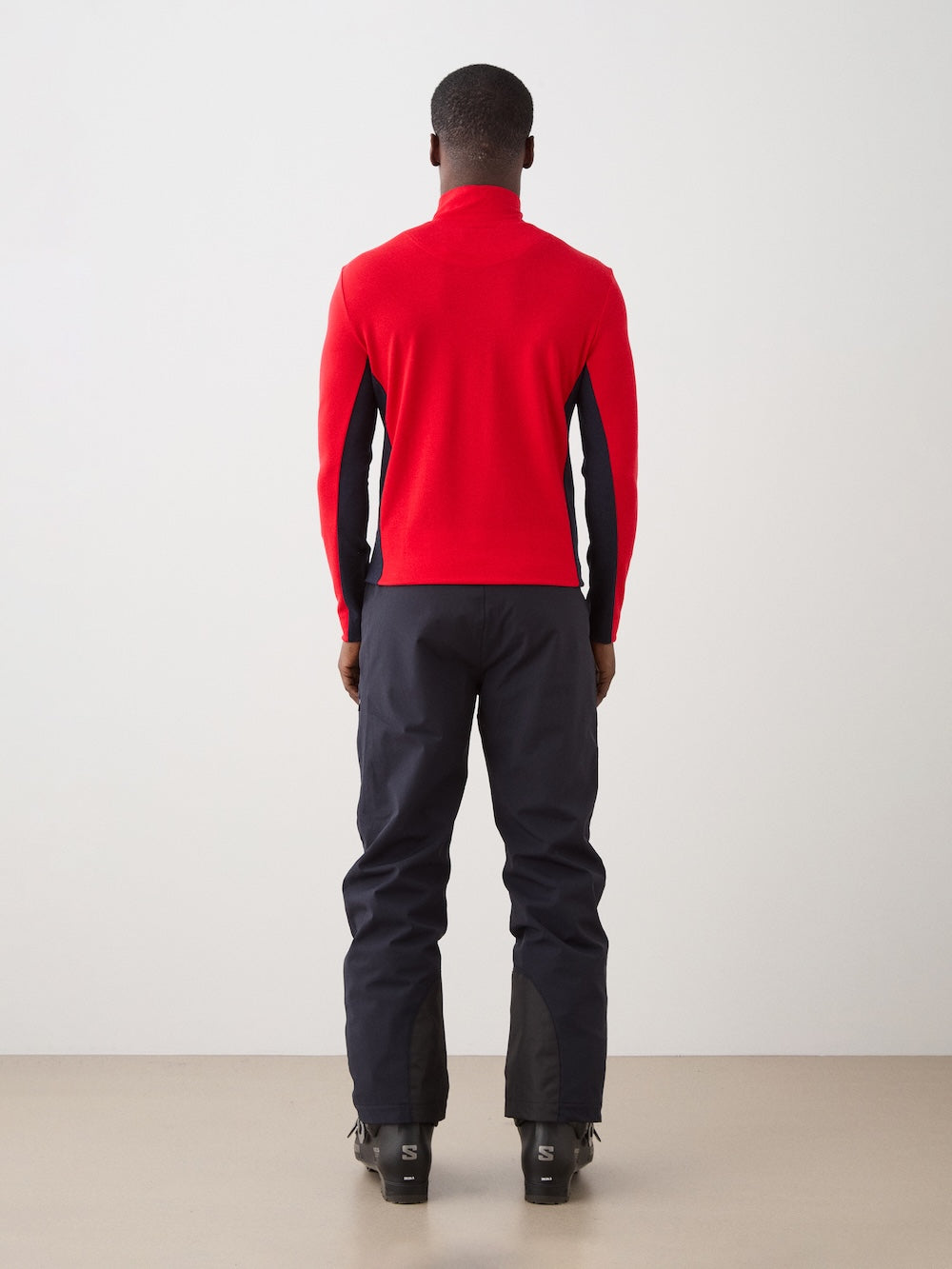 We Norwegians | FW25 | Mens Voss 1/4-Zip_Red | Model is wearing this light weight knitted top with a stand collare, 1/4th zipper opening and long sleeves - paired with black pants on an off-white background | Back