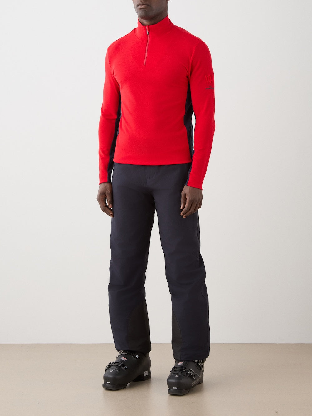 We Norwegians | FW25 | Mens Voss 1/4-Zip_Red | Model is wearing this light weight knitted top with a stand collare, 1/4th zipper opening and long sleeves - paired with black pants on an off-white background | Front