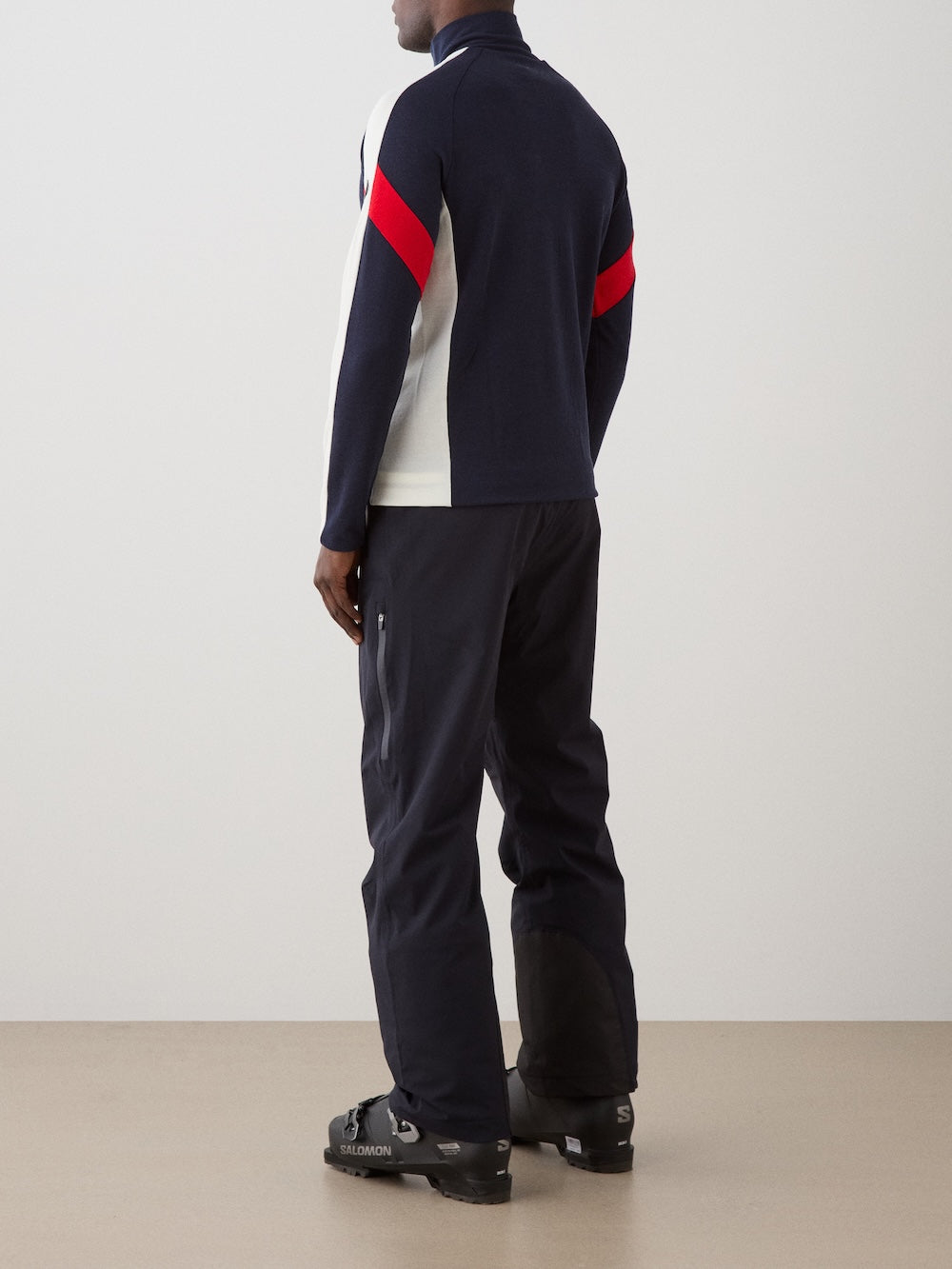 The We Norwegians Zermatt Zipup Men is a navy long-sleeve ski sweater with a quarter-zip, white shoulder and sleeve panels, red diagonal stripes on the upper sleeves, and a small circular logo patch on the left upper arm | Back