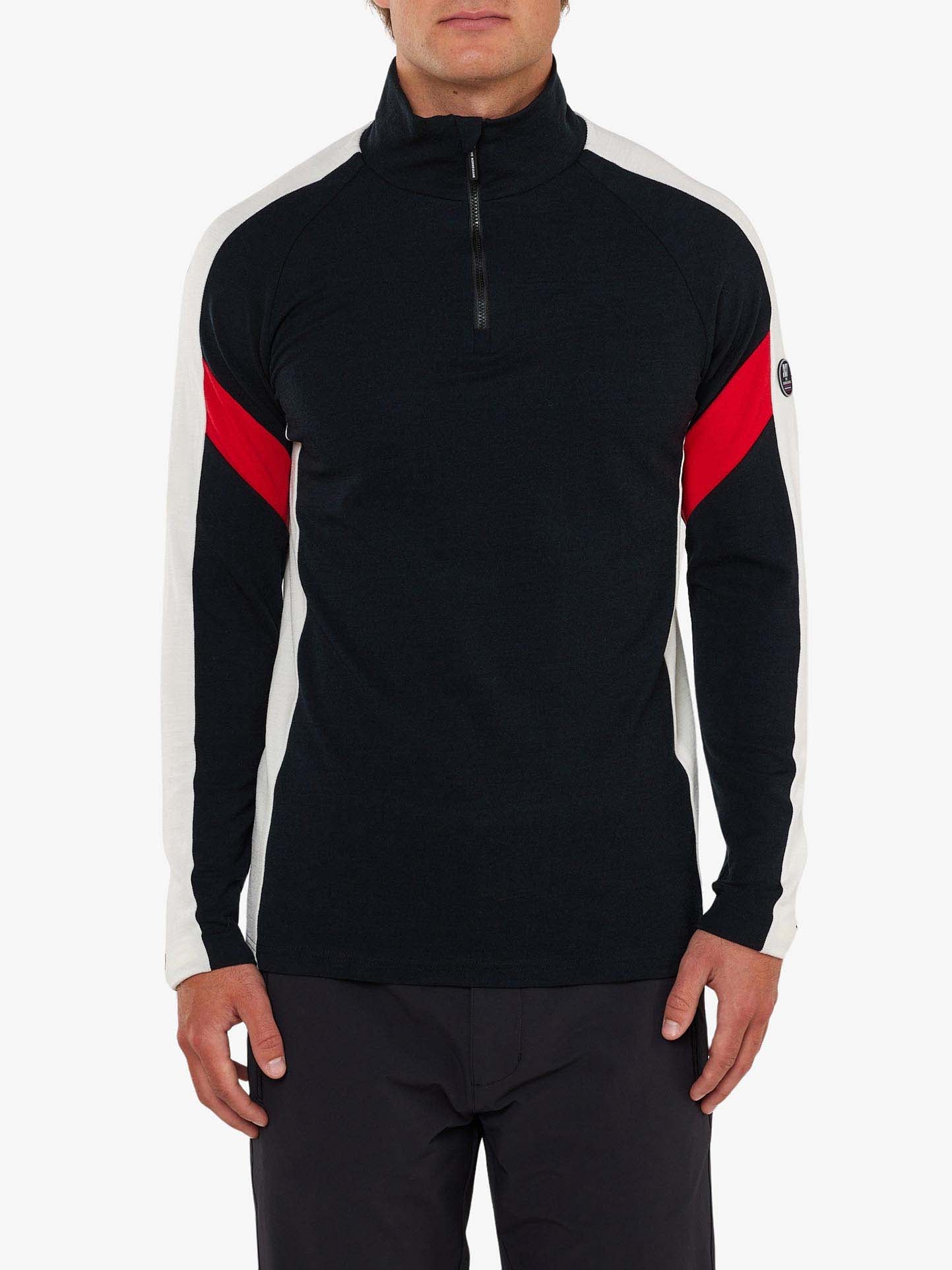 A person is wearing the Zermatt Zipup Men by We Norwegians, a long-sleeve, half-zip pullover shirt made of Superfine Merino wool. The shirt features a predominantly black design with white sleeves and a red stripe across the upper arms, perfectly complementing their black pants. The background is plain and white.