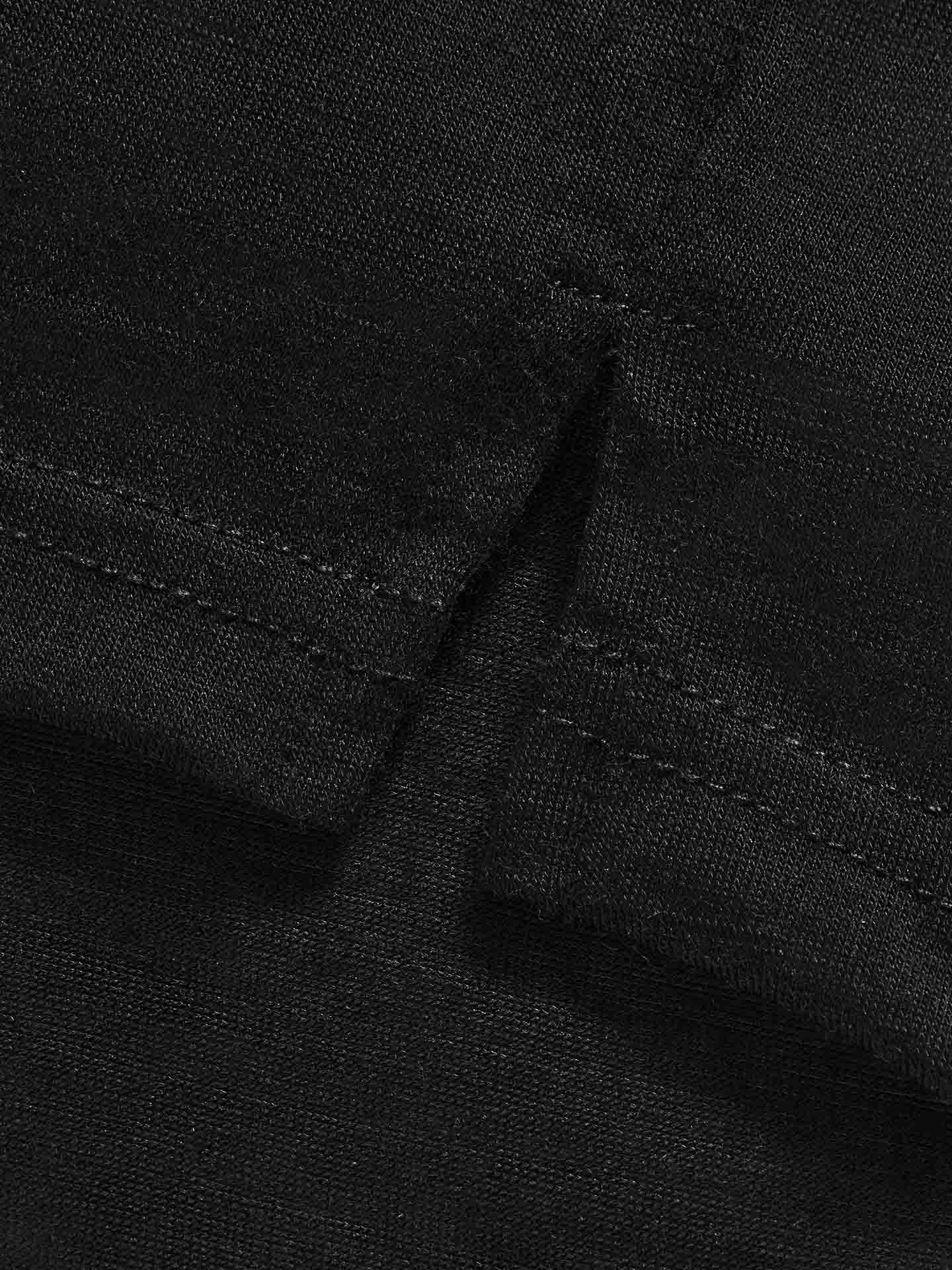 Close-up of We Norwegians' Natt PJs Shorts for Women in black, featuring detailed stitching and a neatly sewn seam. The texture and weave of the Merino wool material are visible, showcasing craftsmanship and durability. The image focuses on the precise intersection of two fabric pieces, revealing an Orion constellation print subtly woven in.