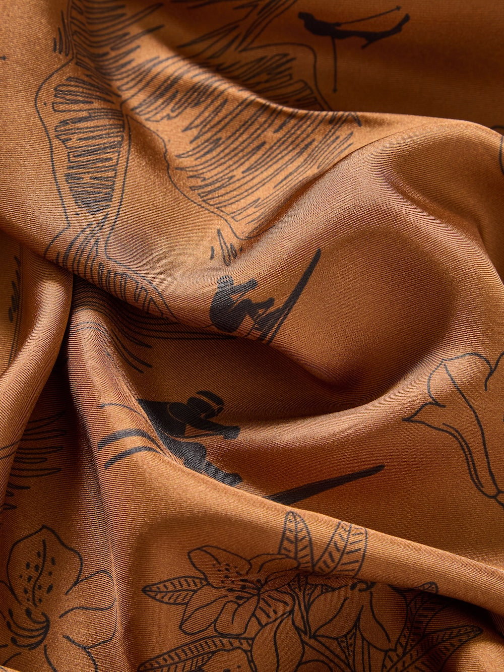 The Alps Silk Scarf by We Norwegians features smooth, satiny brown fabric with black line drawings of flowers, leaves, and surfers in a Scandinavian-inspired design. Its warm earthy tone and soft texture evoke natural elegance.