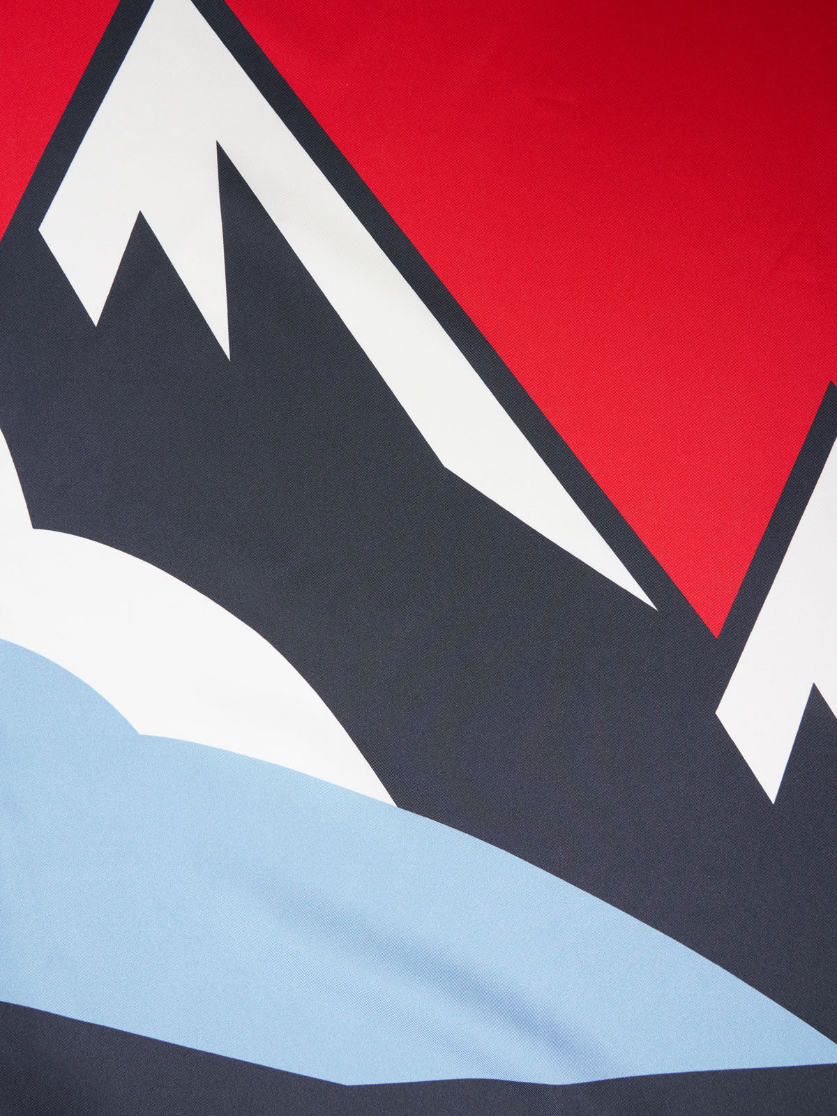 Stylized graphic of a snowy mountain range with sharp, angular peaks. The mountains are black with white snow caps, set against a bright red sky, and a light blue foreground suggesting snow or a lake. Perfect for the Snowfun Silk Scarf collection by We Norwegians, this bold and minimalist design stands out on pure silk.