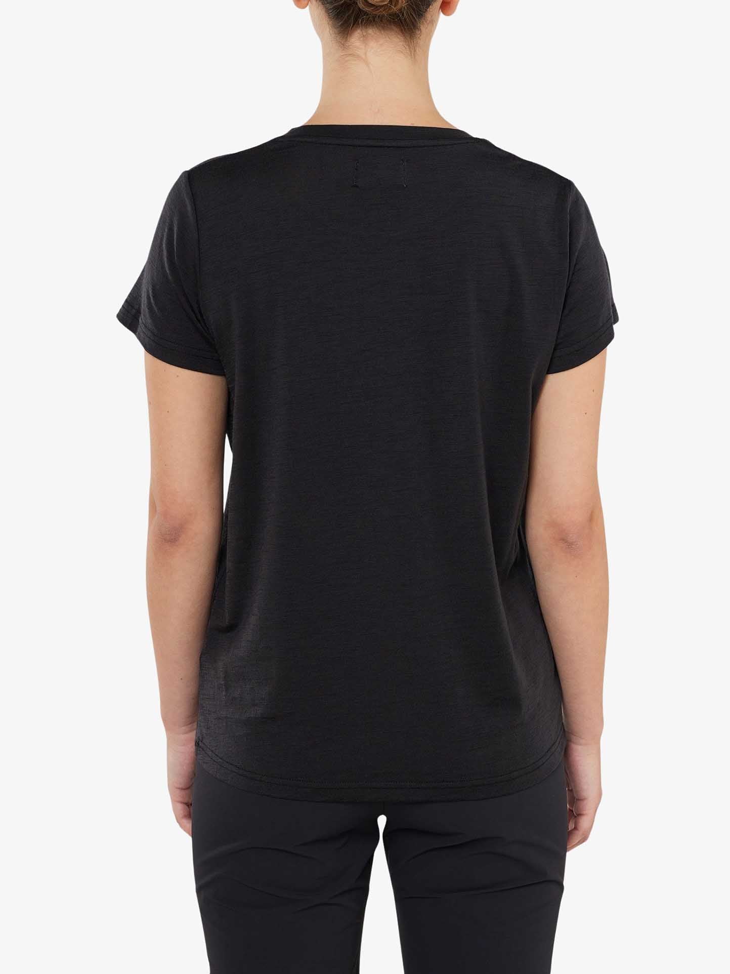 A person is standing with their back to the camera, wearing a black short-sleeve Berg Favorite Tee Women from We Norwegians and black pants. The background is plain white, and the person's hair is tied in a bun. This no-itch fabric ensures a comfortable fit for all-day wear.