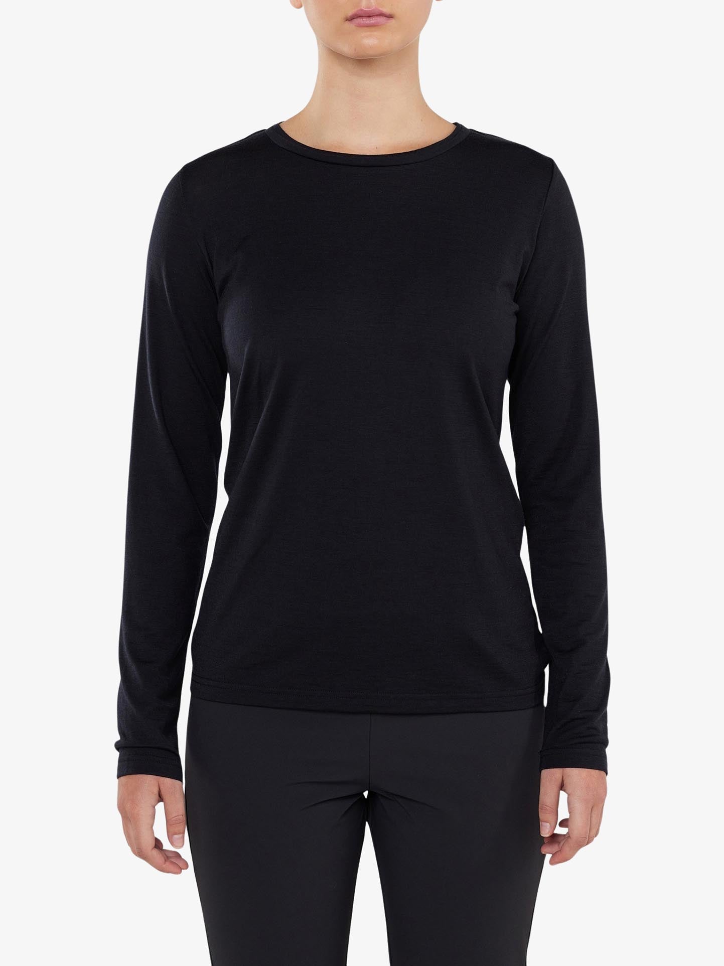 A person wearing the Berg LongSleeve Women shirt by We Norwegians, paired with black pants, stands against a white background. The image is cropped to show from the person's shoulders to mid-thigh, with their arms relaxed by their sides.