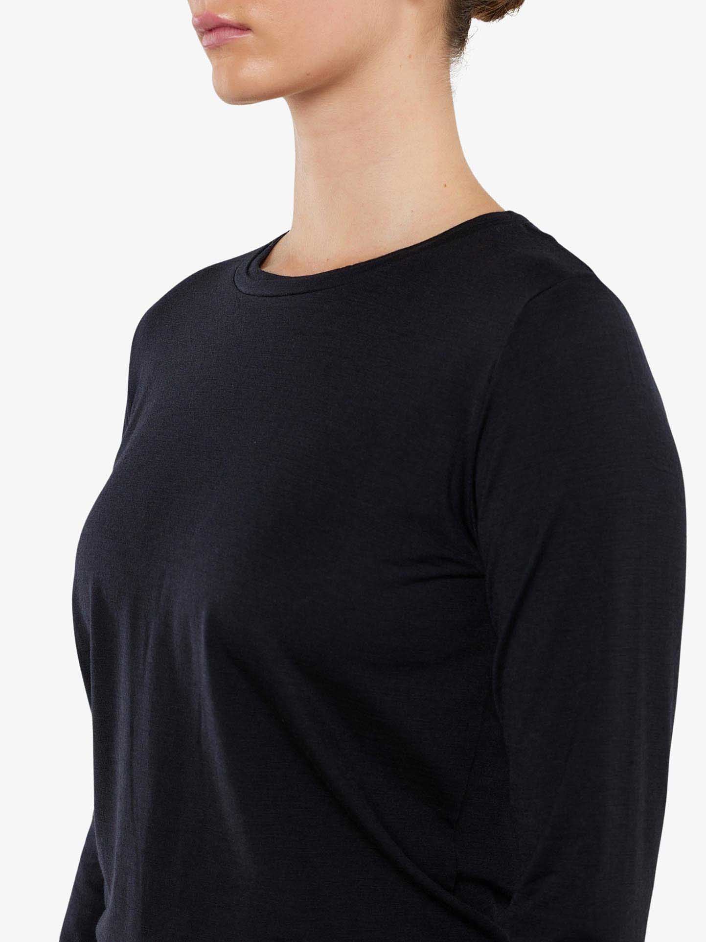 A person with short, light brown hair wearing a plain black Berg LongSleeve Women shirt by We Norwegians. The photo captures a side profile from the neck to mid-torso against a solid white background.